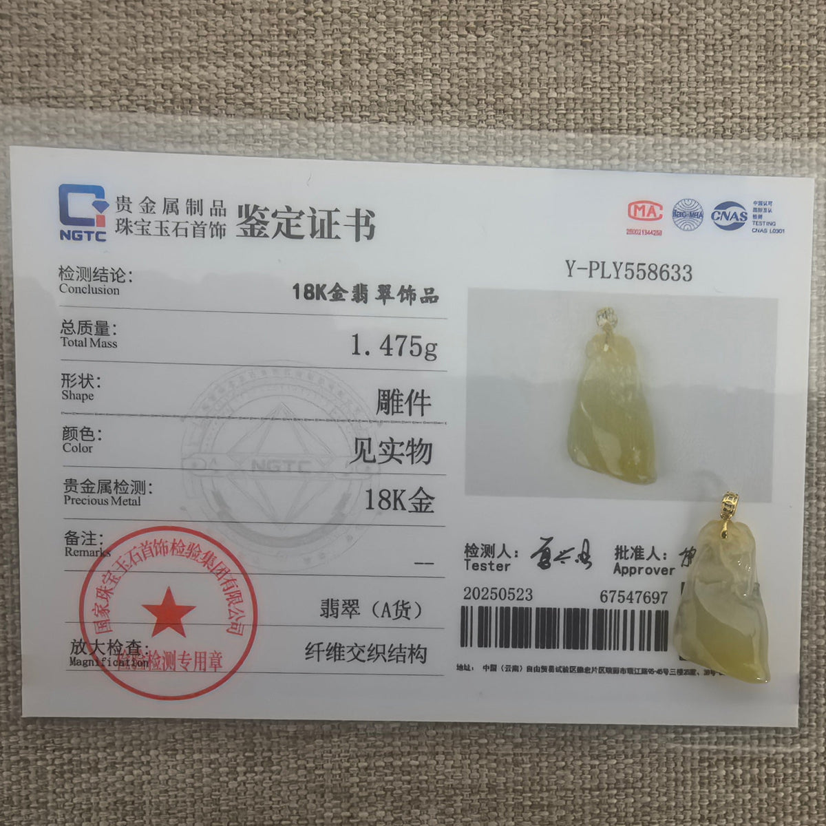 Yellow jadeite Horse Head Pendant with its 18K gold bail beside the matching NGTC certificate on a woven surface.