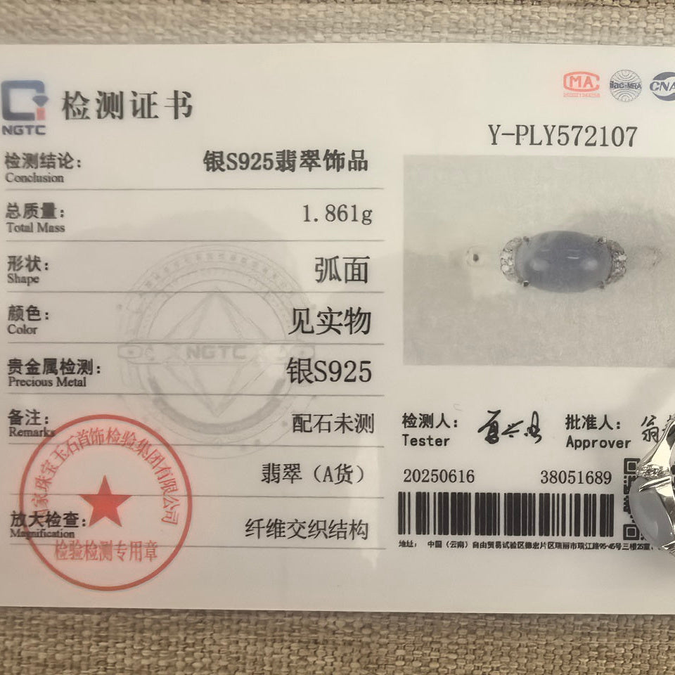 Purple jadeite ring displayed with its matching NGTC certificate on a woven fabric background.