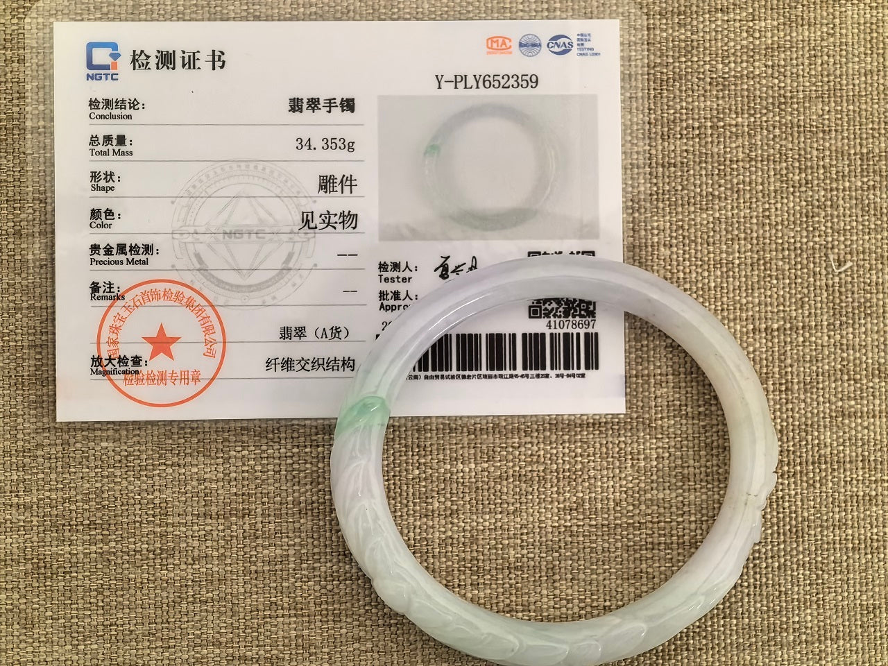 NGTC certified glutinous white-and-green carved oval jadeite bangle shown with matching certificate.