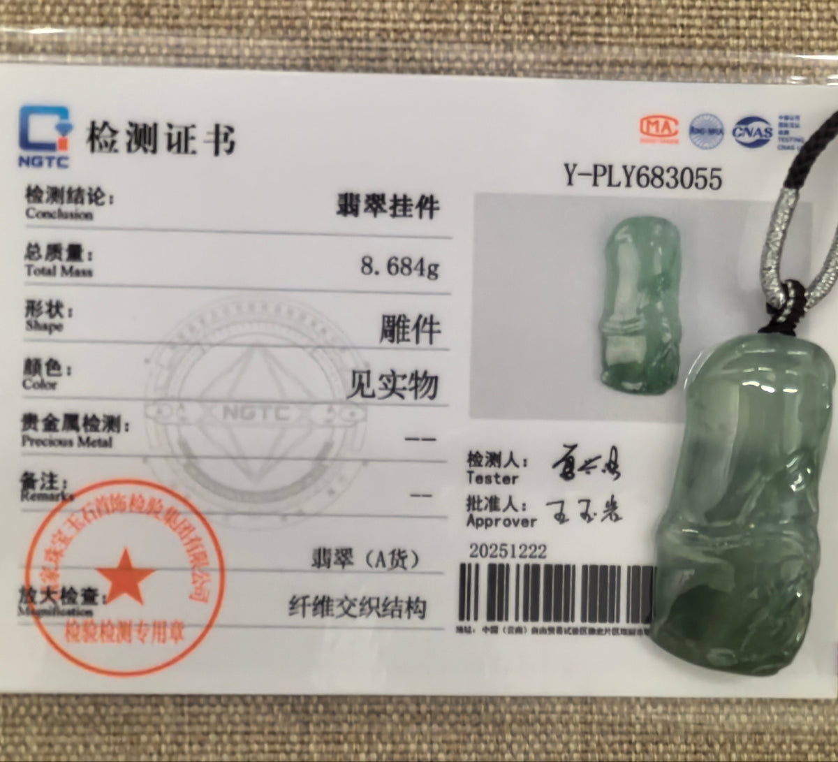 Green jadeite Bamboo Pendant displayed with its matching NGTC certificate on a woven background.