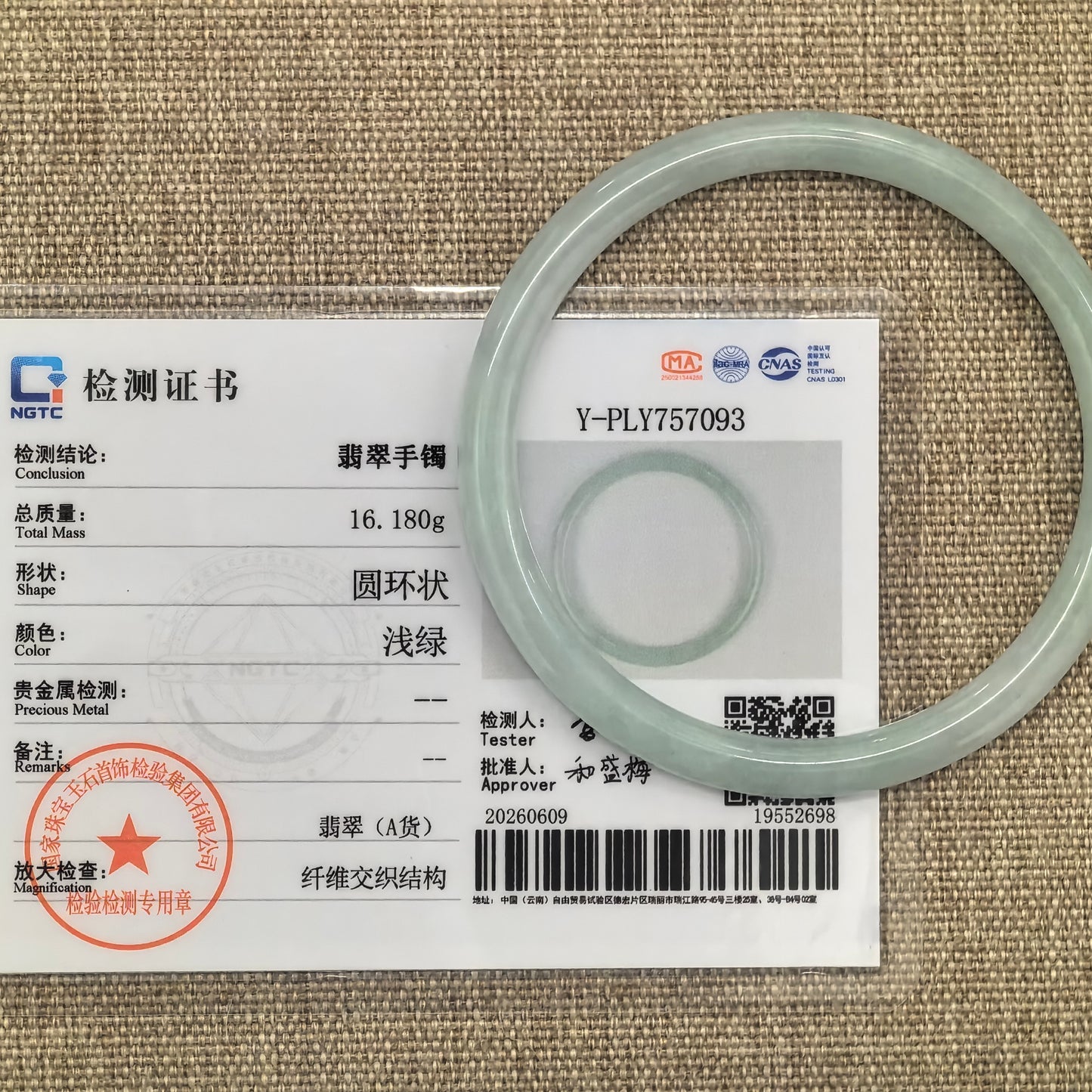 Natural Grade-A light green jadeite bangle displayed on stone background.