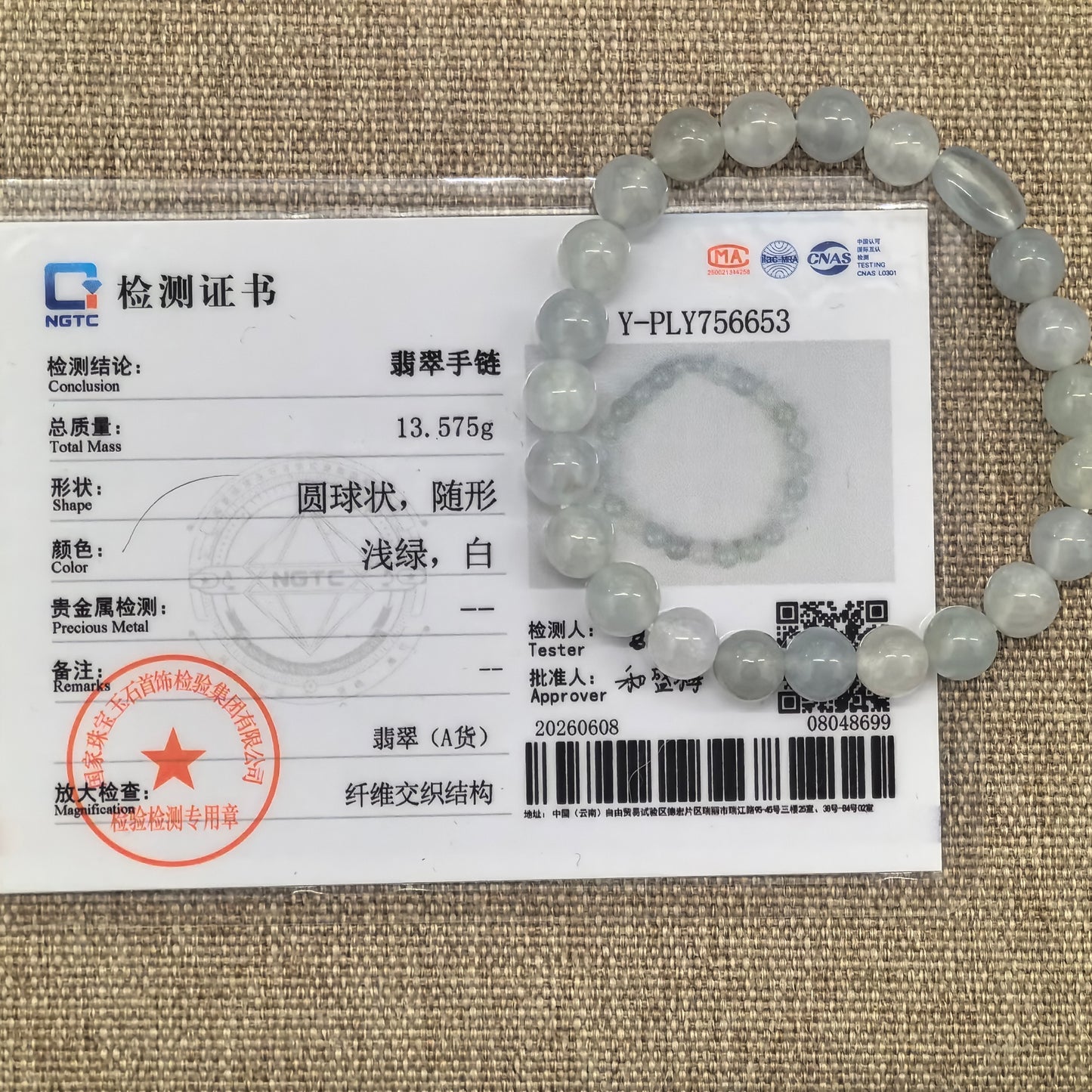 NGTC certified white jadeite bead bracelet shown with matching certificate and 13.575 g weight.