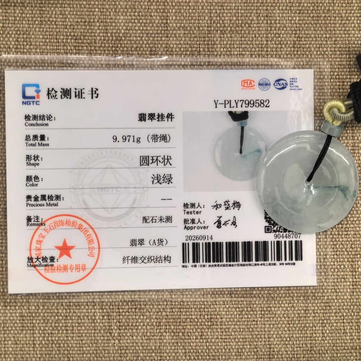 Pale green jadeite Peace Pendant beside its matching NGTC certificate, which identifies the main pendant as Grade-A jadeite and notes that accessory stones were not tested.