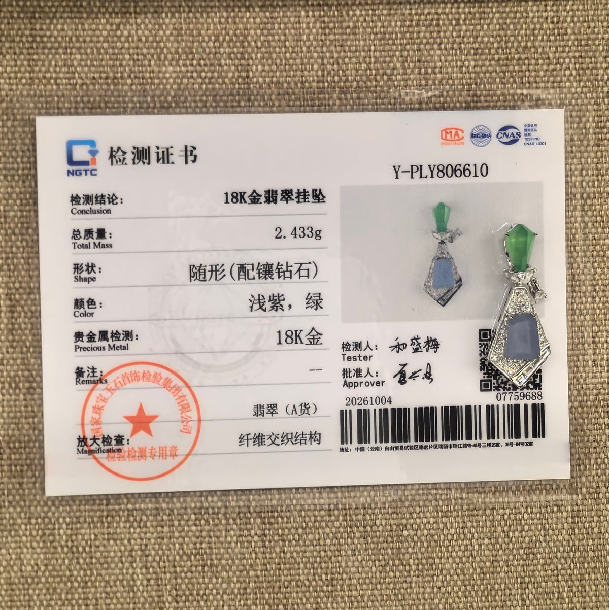 Lavender and green jadeite geometric kite-shaped pendant beside its matching NGTC certificate, number Y-PLY806610, on a woven background.