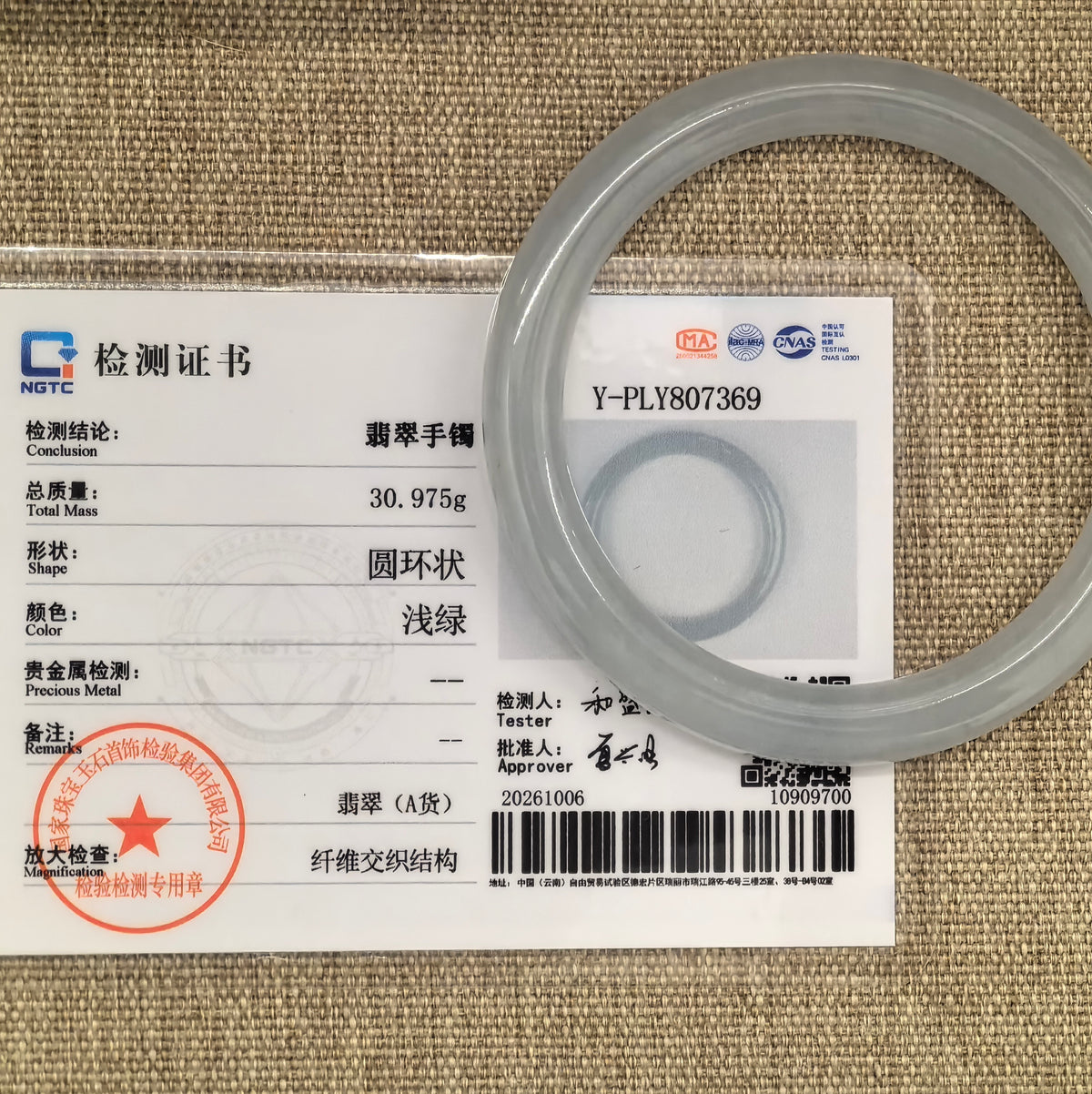 White jadeite round-bar bangle with a pale green undertone displayed with its matching NGTC certificate.