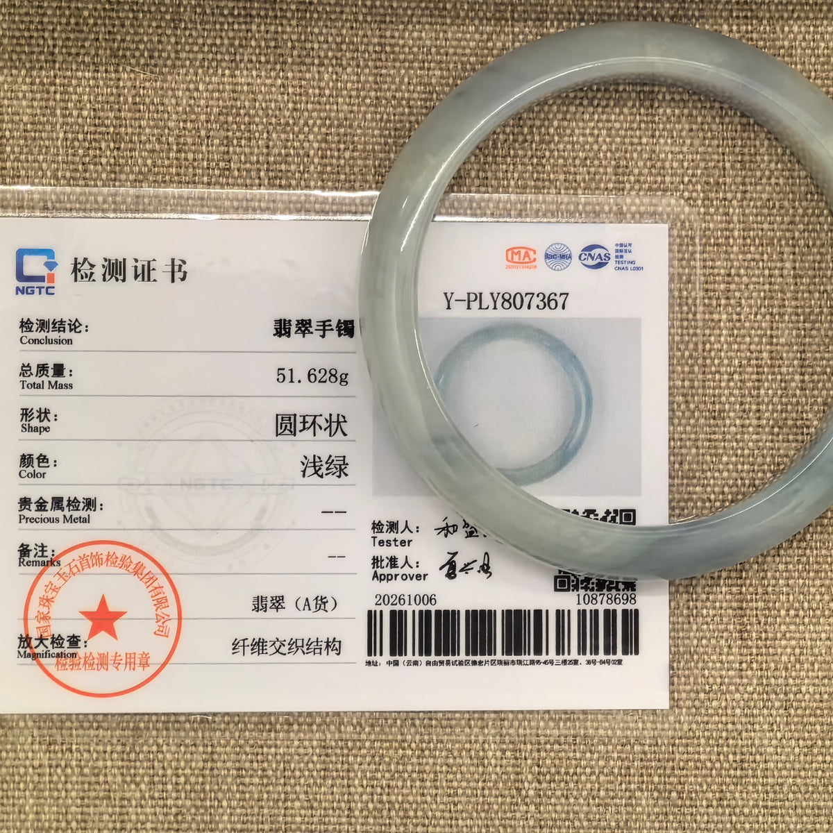 Denim blue jadeite D-shape bangle with floating patterns displayed with its matching NGTC certificate.