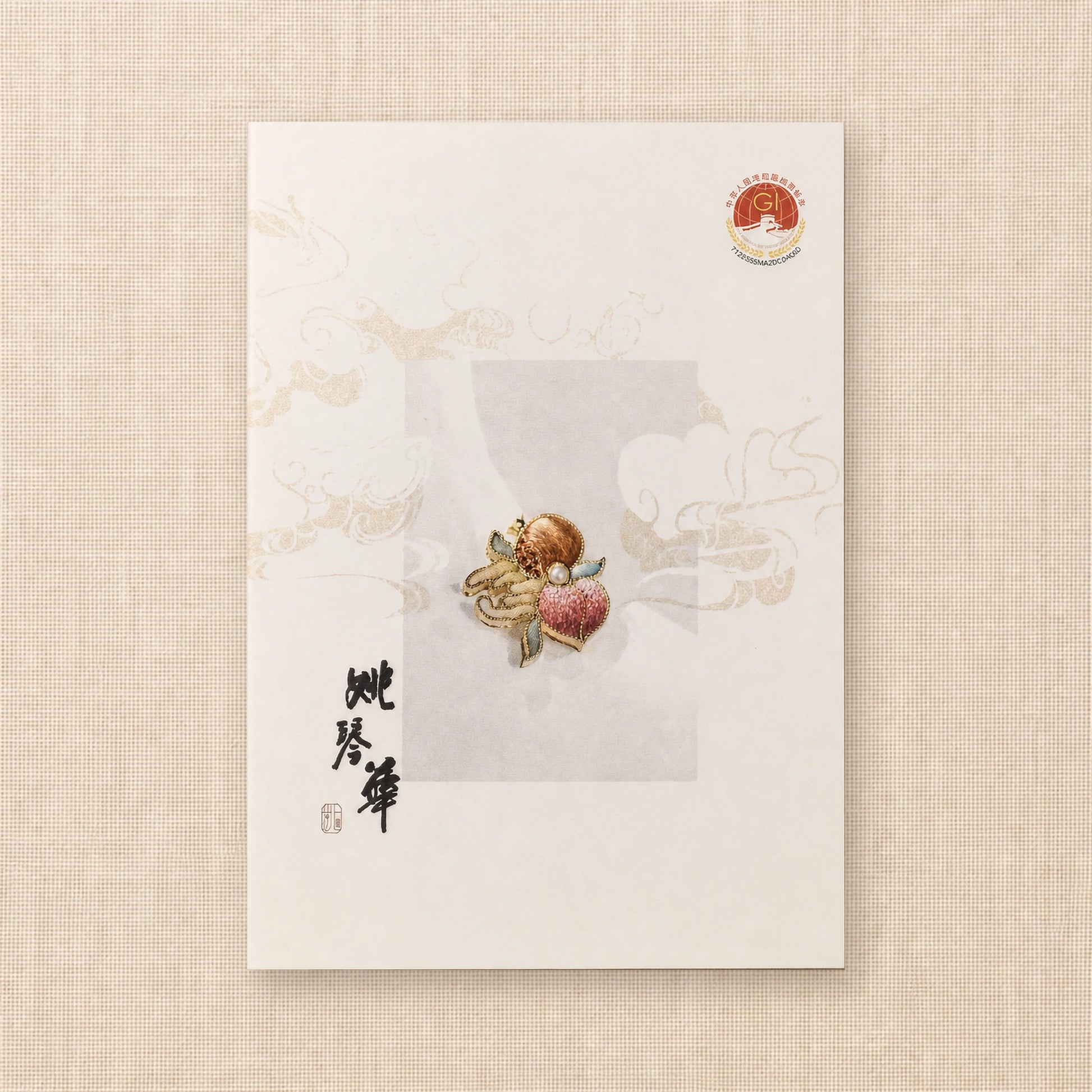 Suzhou silk embroidery Three Blessings brooch pendant displayed on a cream presentation card with pomegranate, Buddha’s hand and longevity peach motifs.