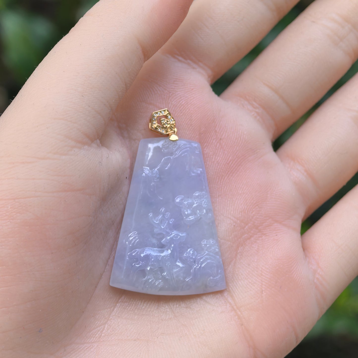 Natural Grade-A icy glutinous purple deer plaque jadeite pendant with 18K gold setting shown in hand.
