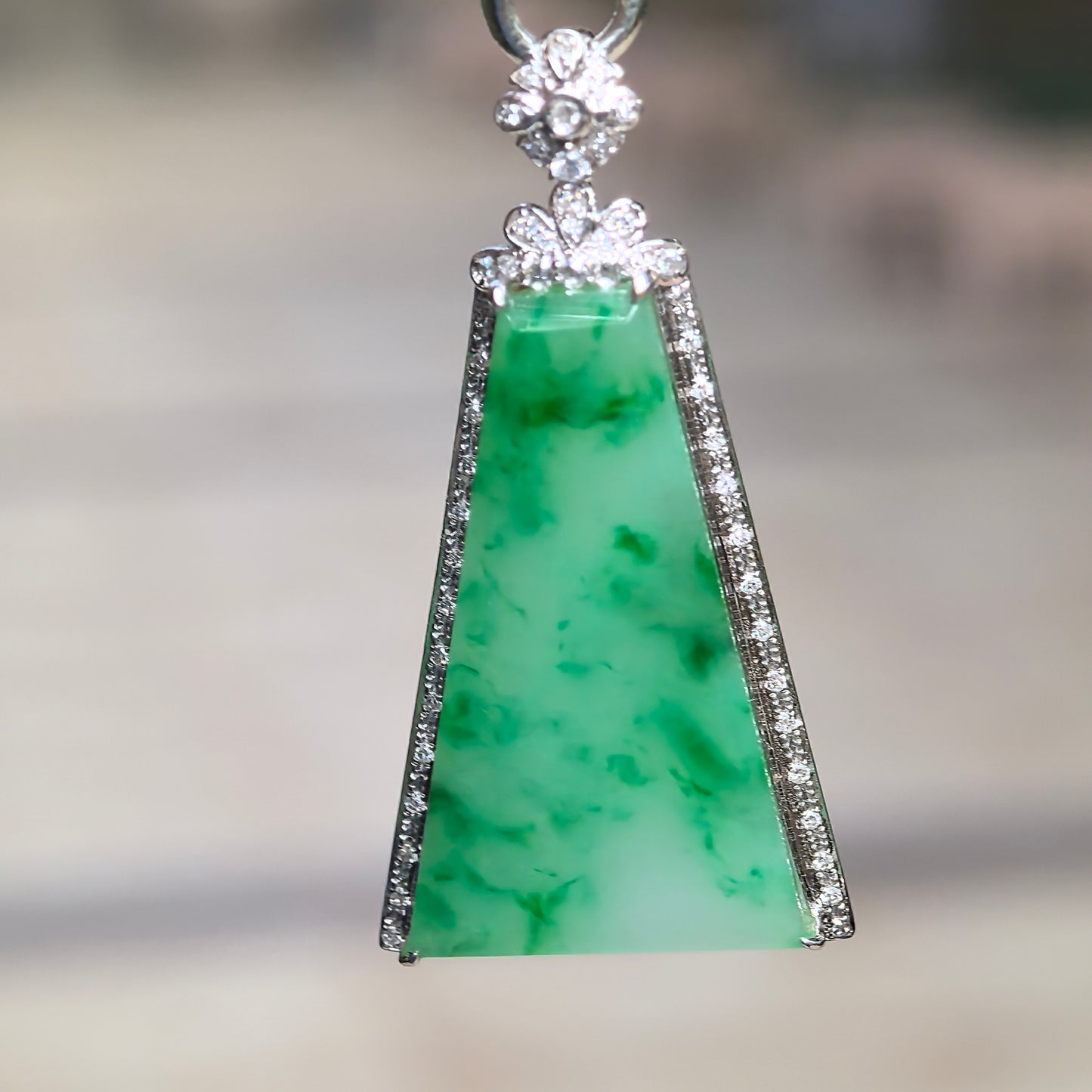 Close-up of vivid green floating flower jadeite Plain Jade Plaque pendant in diamond-accented 18K gold setting.
