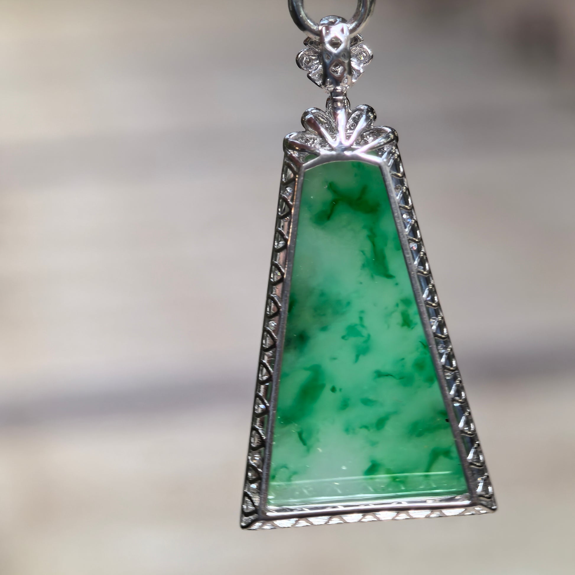 Back view of trapezoid green floating flower jadeite pendant showing 18K gold setting and polished surface.

