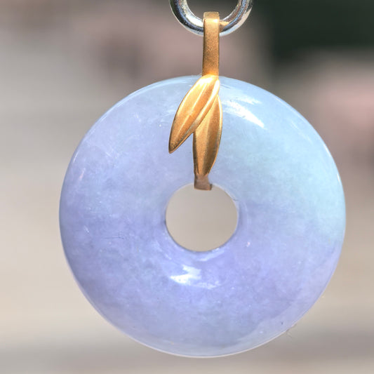 Close-up of purple donut jadeite pendant showing soft color, smooth polish, and rounded circular shape.
