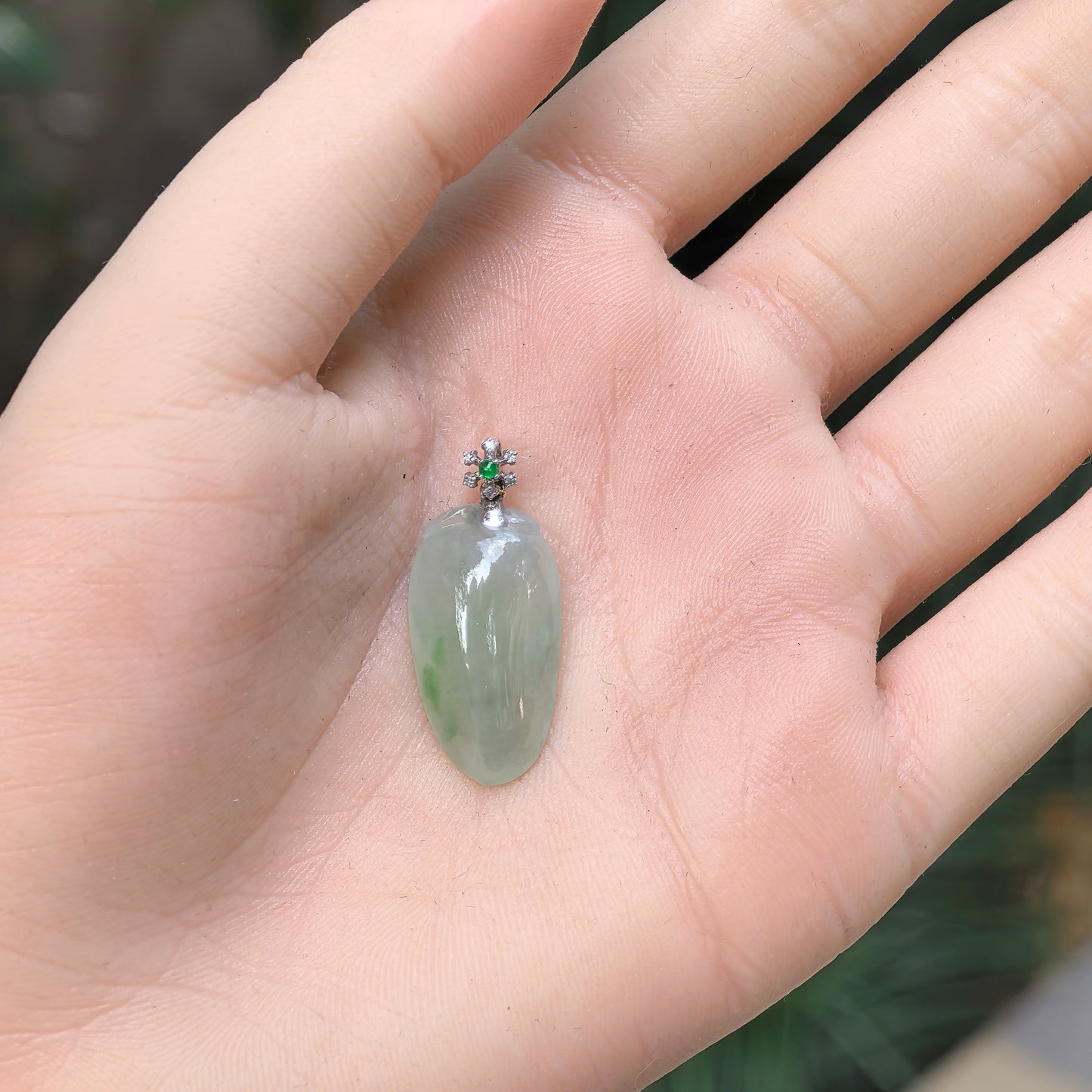 Natural Grade-A icy glutinous light green melon jadeite pendant with 18K gold and green accent shown in hand.