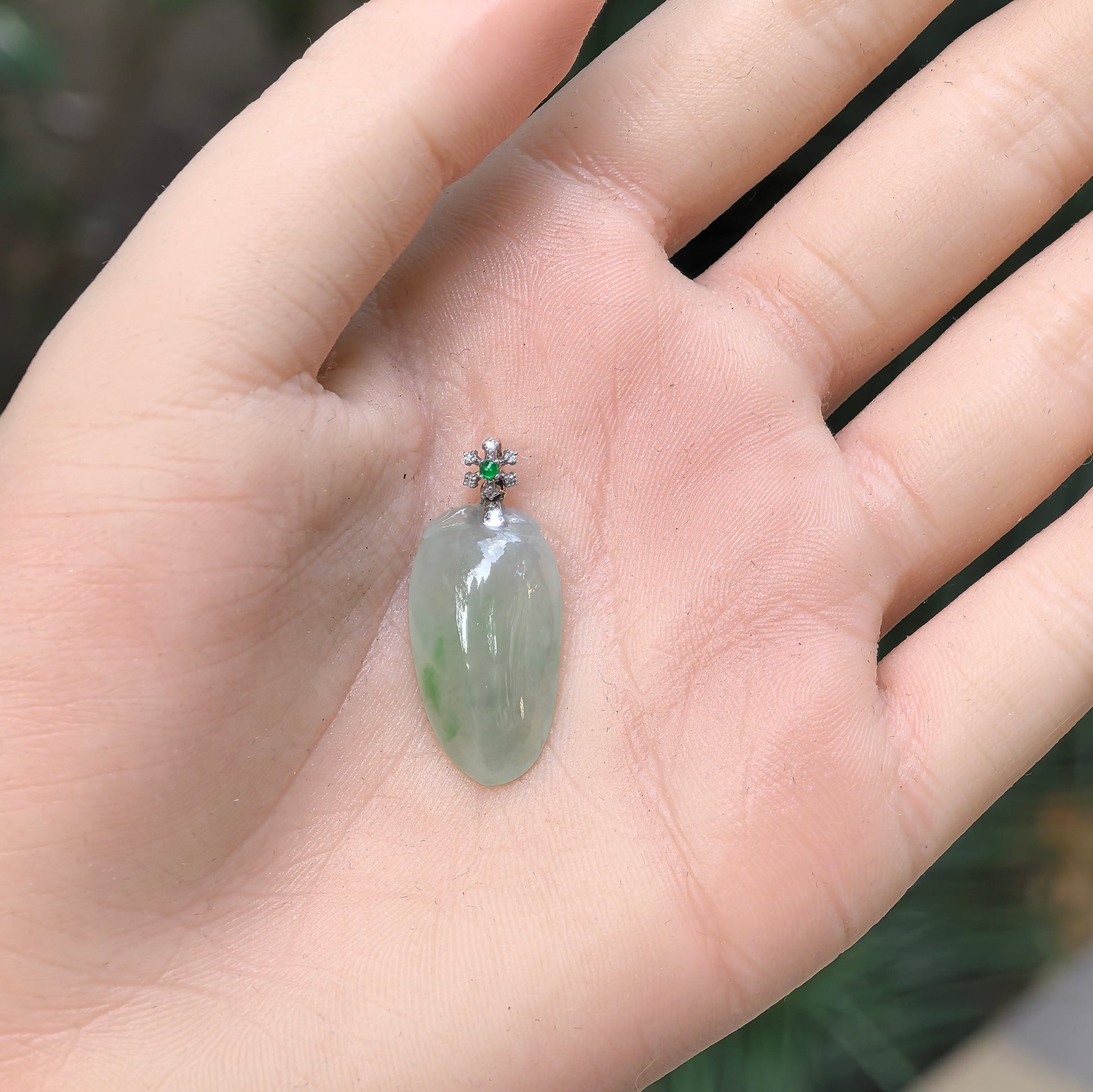 Natural Grade-A icy glutinous light green melon jadeite pendant with 18K gold and green accent shown in hand.