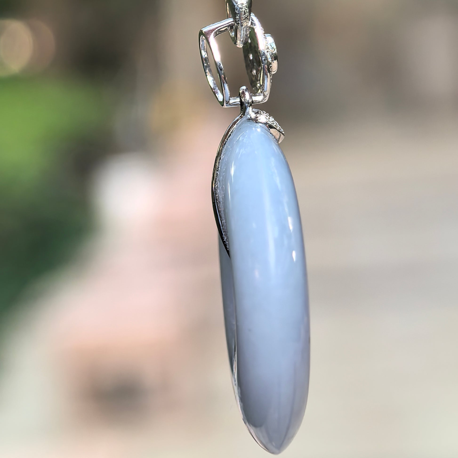 Side view of fine glutinous purple jadeite Peace Pendant showing polished thickness and 18K gold mounting.
