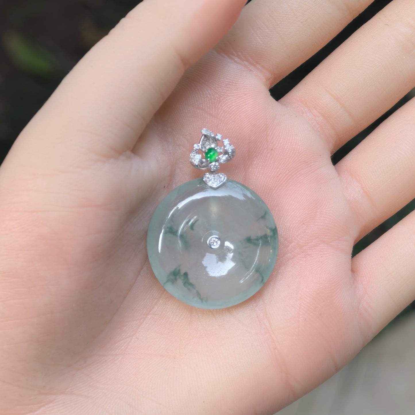 Handheld Natural Grade-A floating green jadeite Peace Pendant with diamond-accented 18K gold setting.
