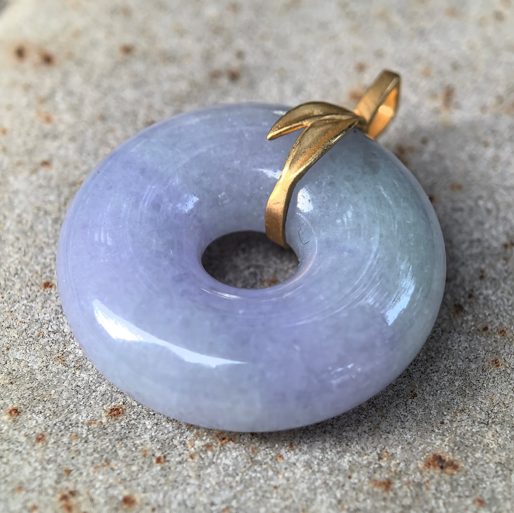 Side view of glutinous purple jadeite donut pendant showing domed thickness and 18K gold bail.
