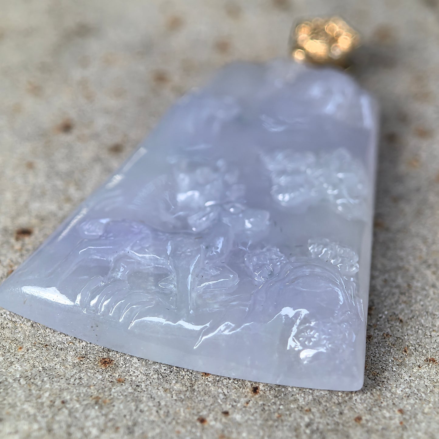 Side view of 18K gold set purple jadeite deer plaque pendant showing polished thickness and texture.
