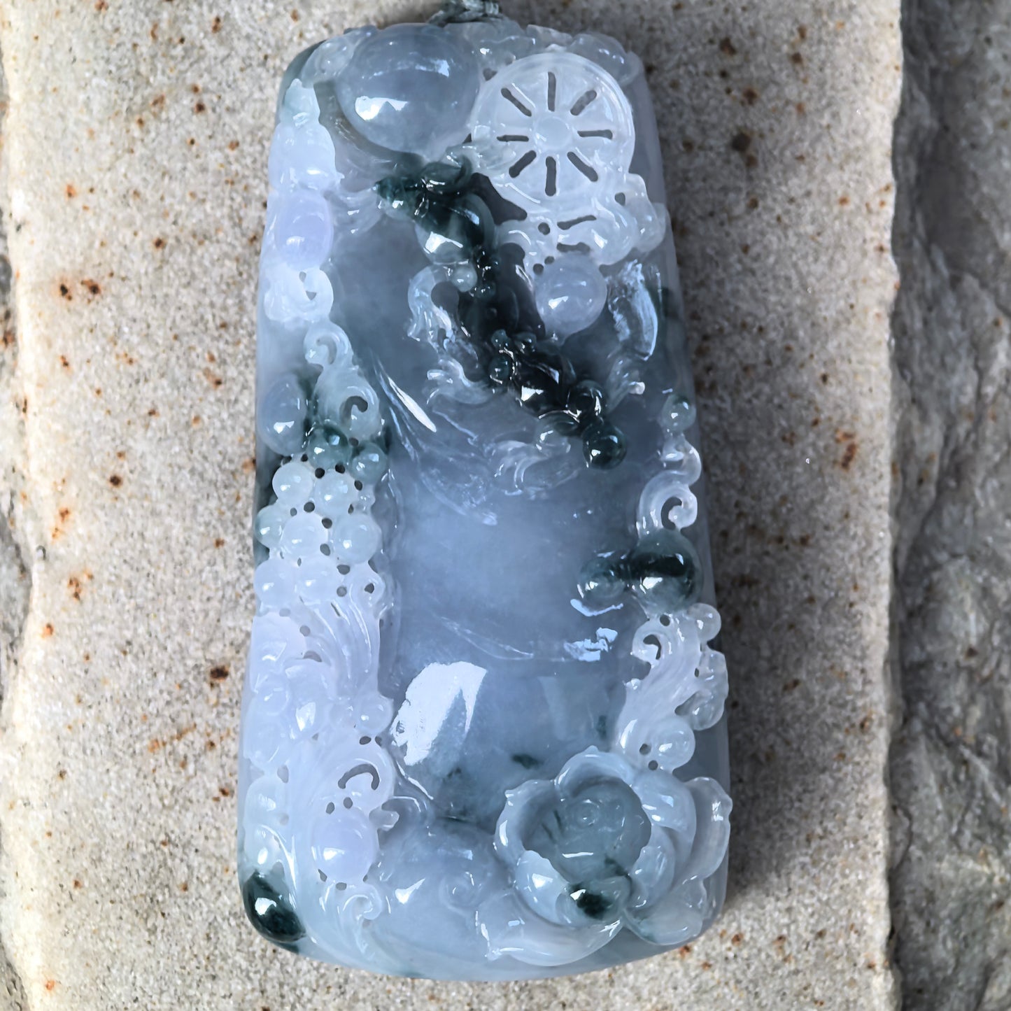 Close-up of glutinous-icy blue-purple jadeite pendant with lotus carving and dark green floating floral patterns