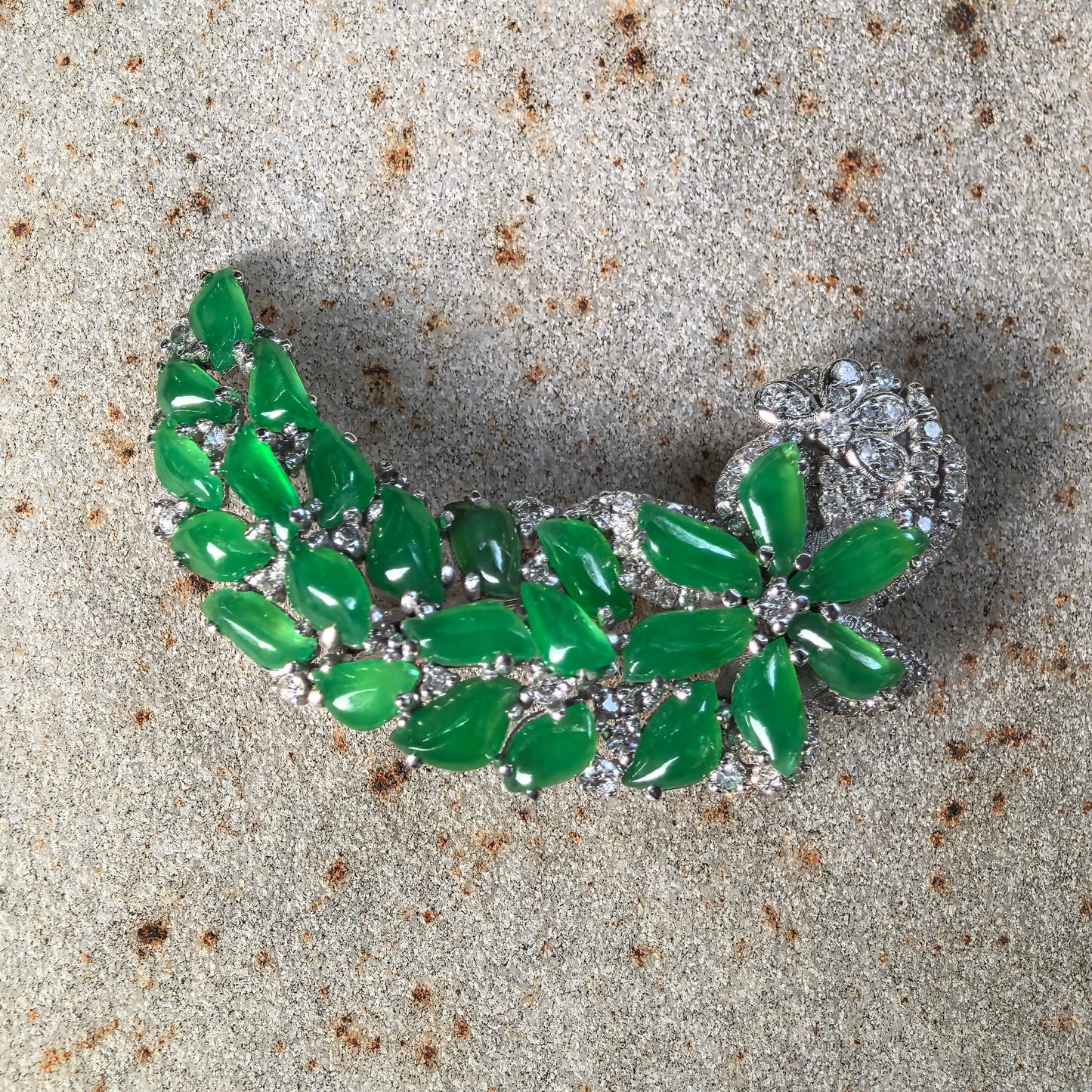 Natural Grade-A icy green 18K gold jadeite brooch with diamond accents displayed on stone background.