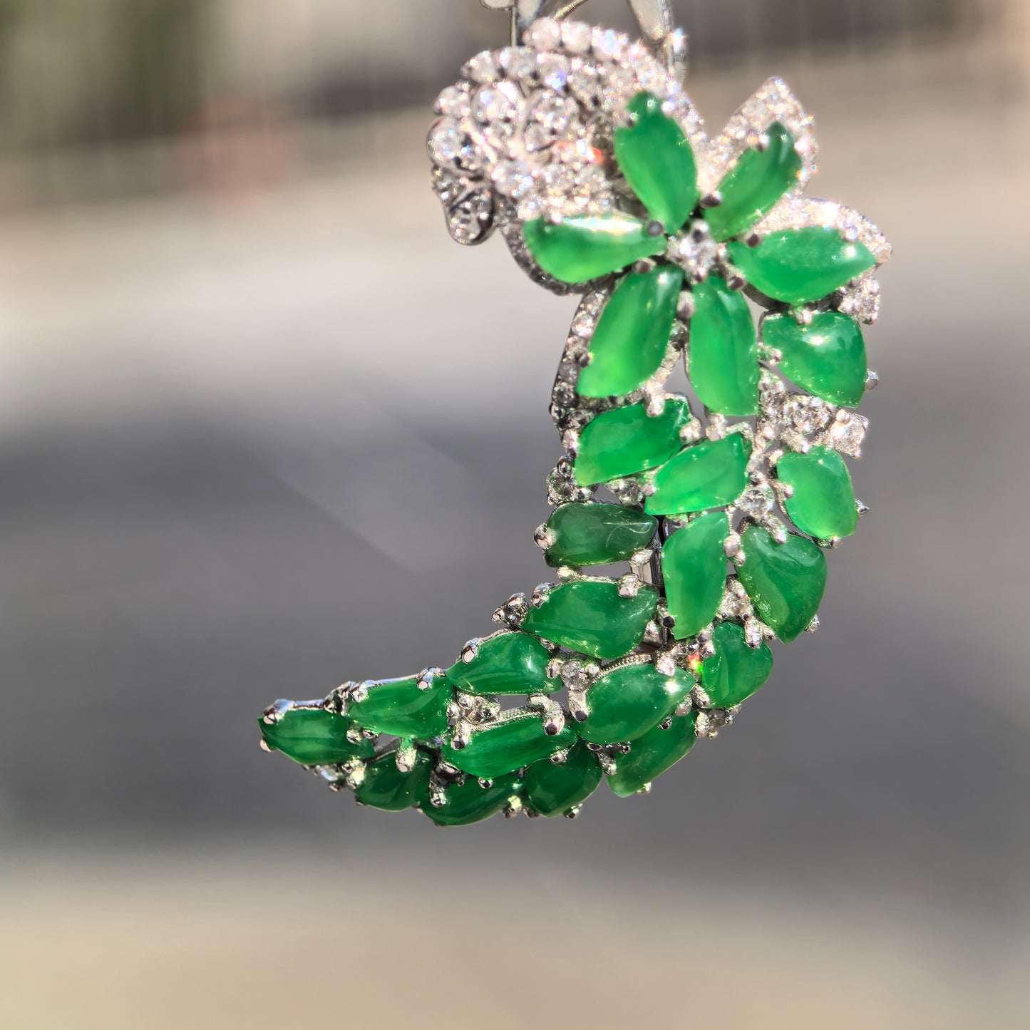 Close-up of icy green jadeite brooch showing leaf-shaped inlay and diamond-accent setting.