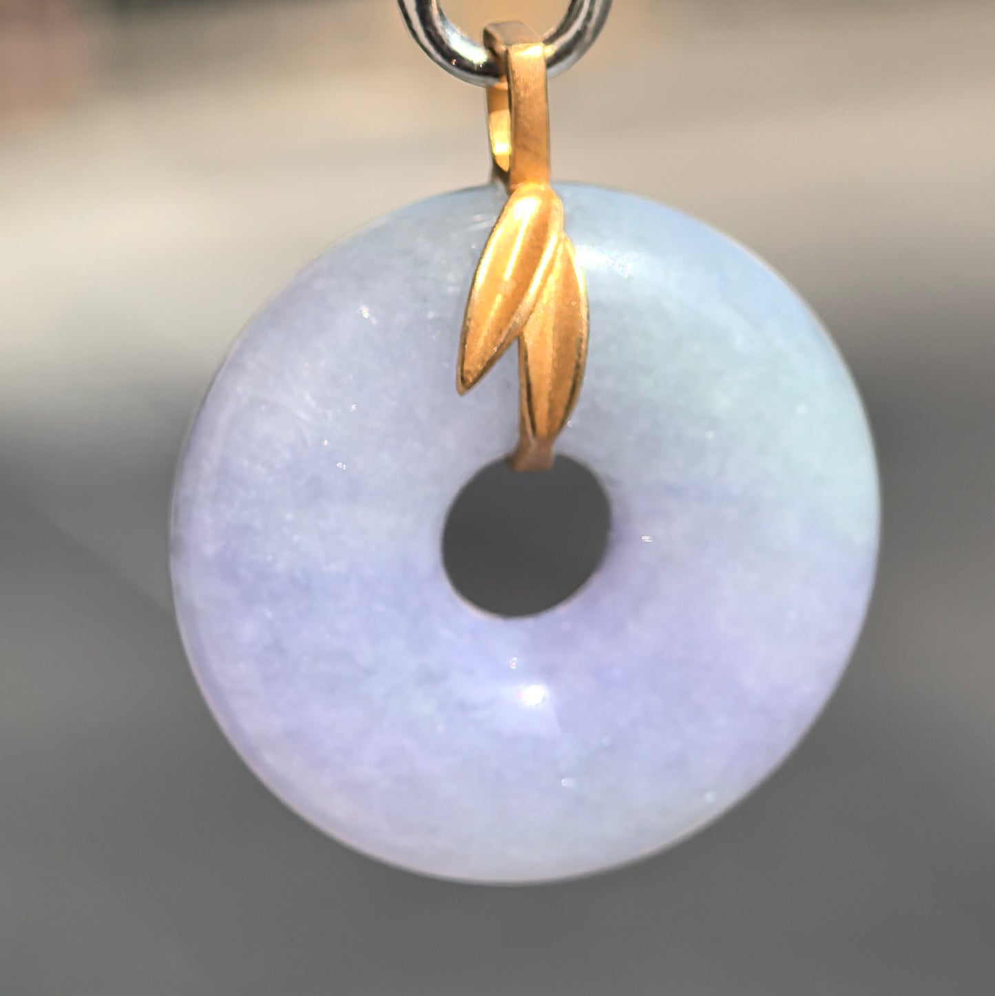Macro detail of purple jadeite donut pendant with glossy surface and delicate glutinous texture.
