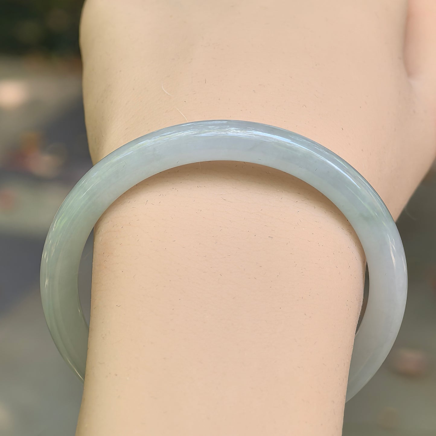 Close-up of light green jadeite bangle showing smooth luster and clean round shape.