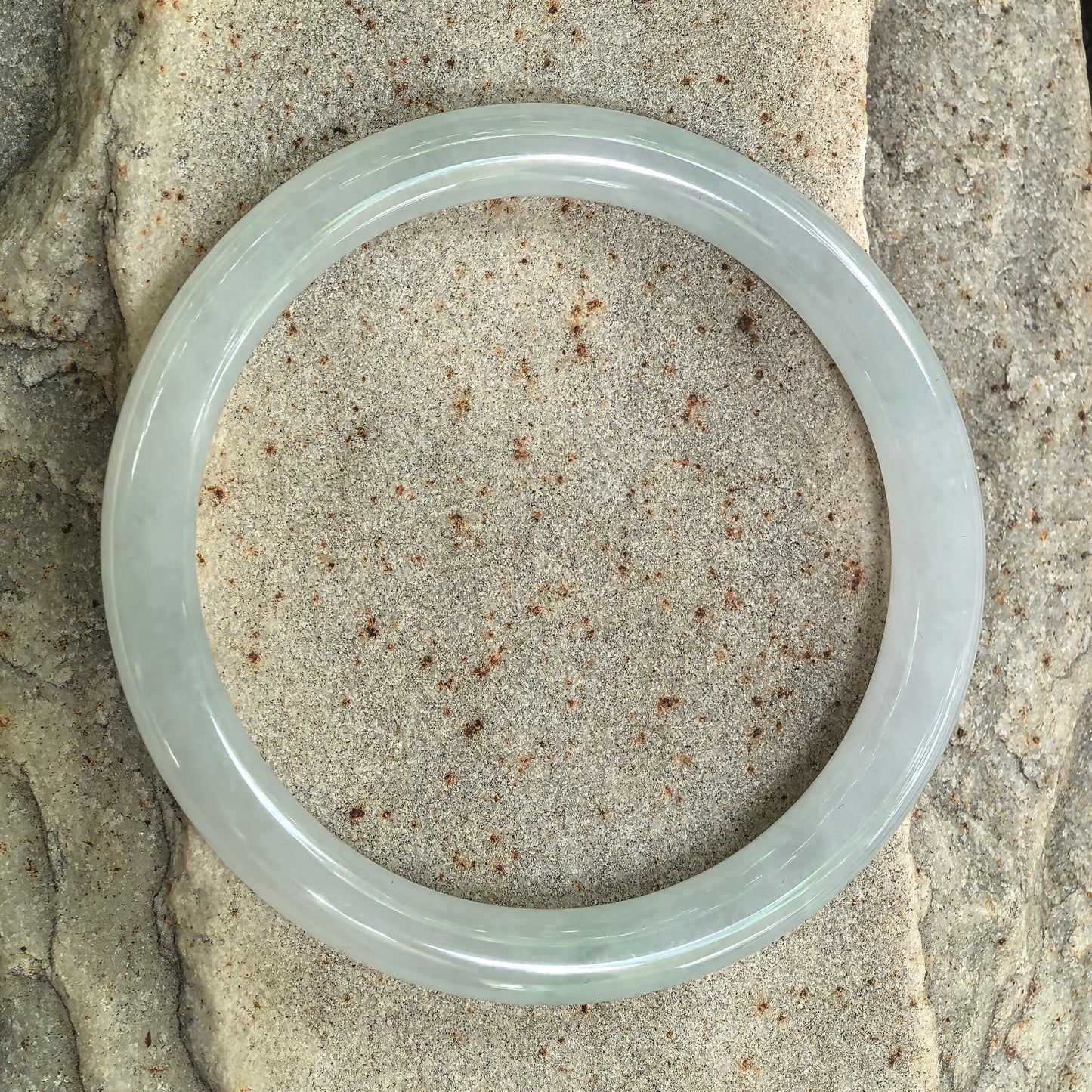 Top view of natural jadeite round bangle showing pale green tone and circular form.