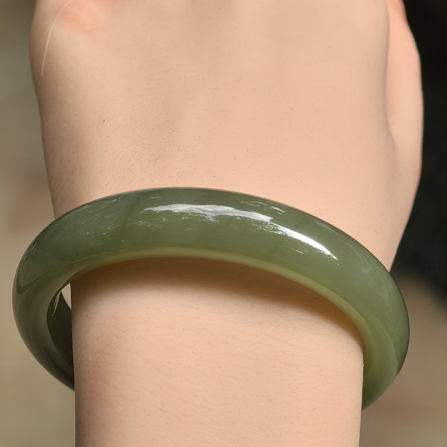 Olive green Hetian jade bangle on wrist
