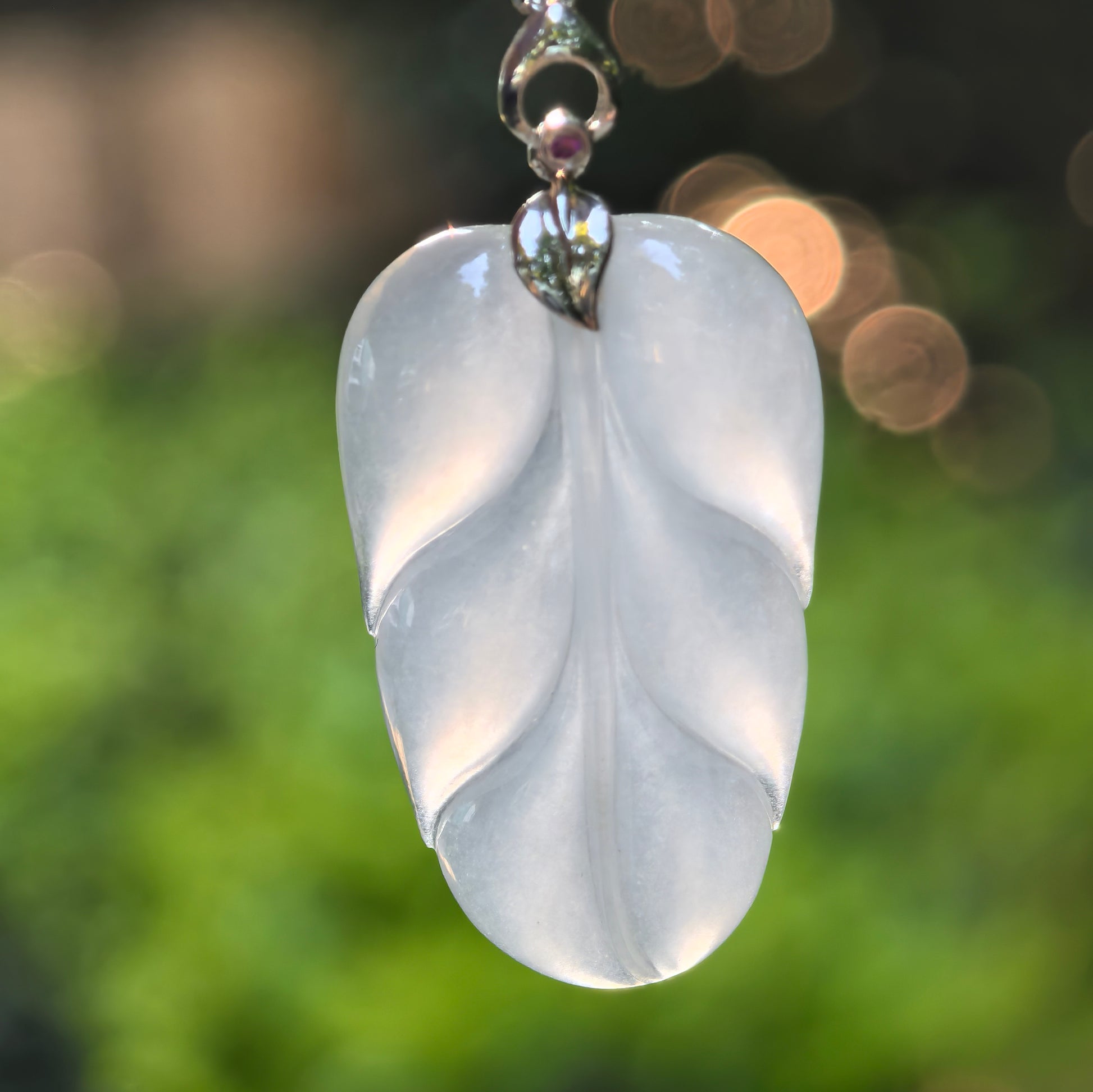 Close-up of icy white jadeite leaf pendant showing carved leaf veins and smooth polished surface.