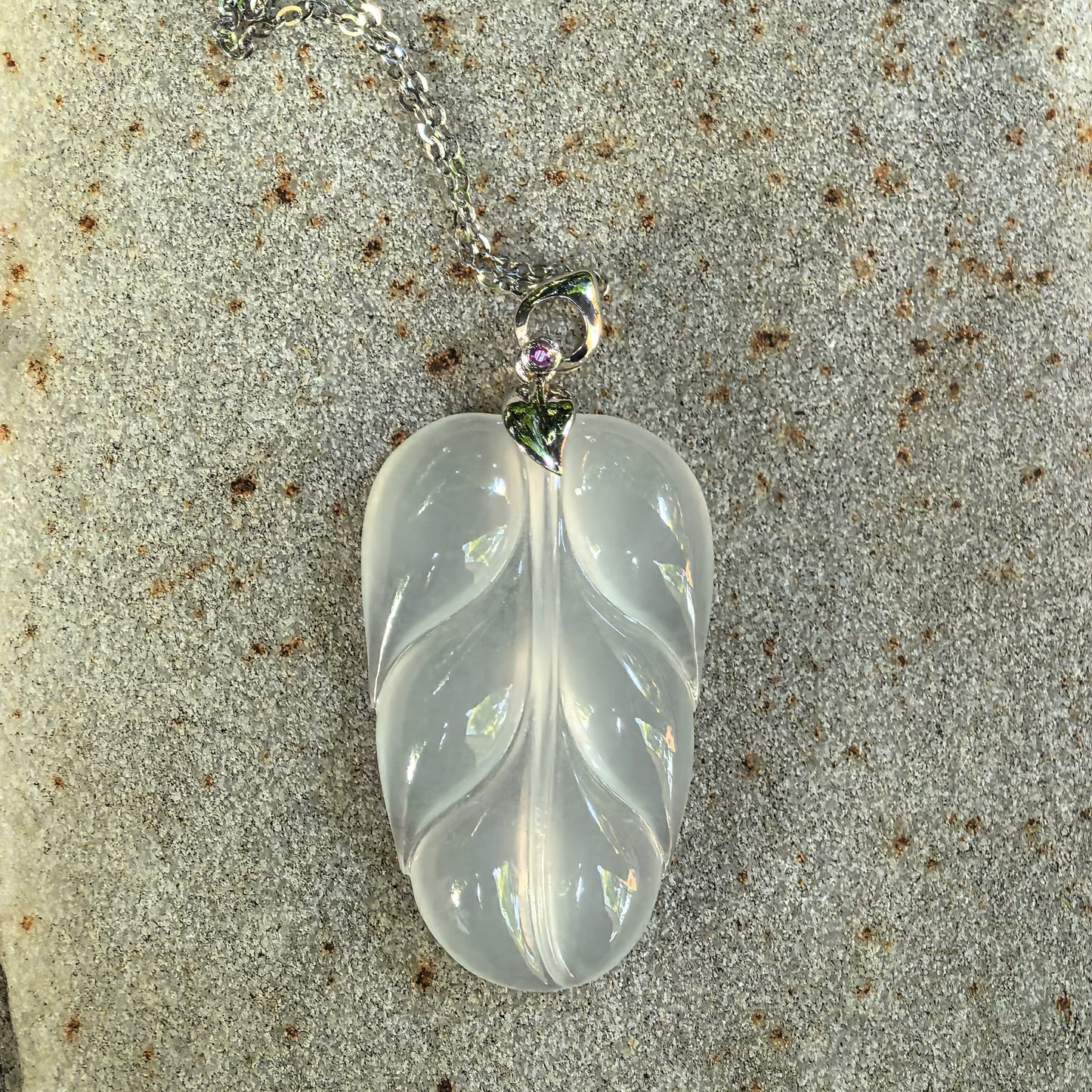 Icy white Burmese jadeite leaf pendant with 18K gold bail and delicate jewelry details.