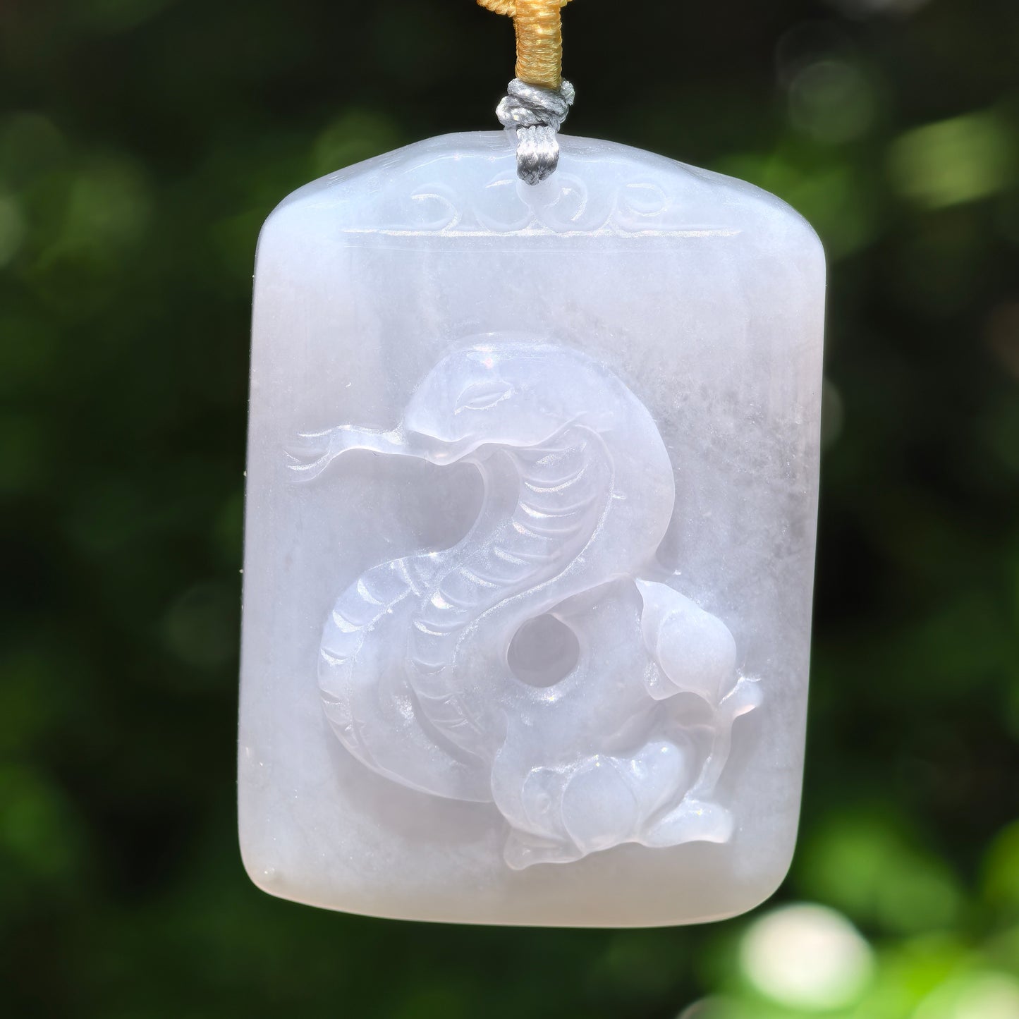 Natural Grade-A white jadeite snake pendant hanging on cord, front view with soft glutinous texture.