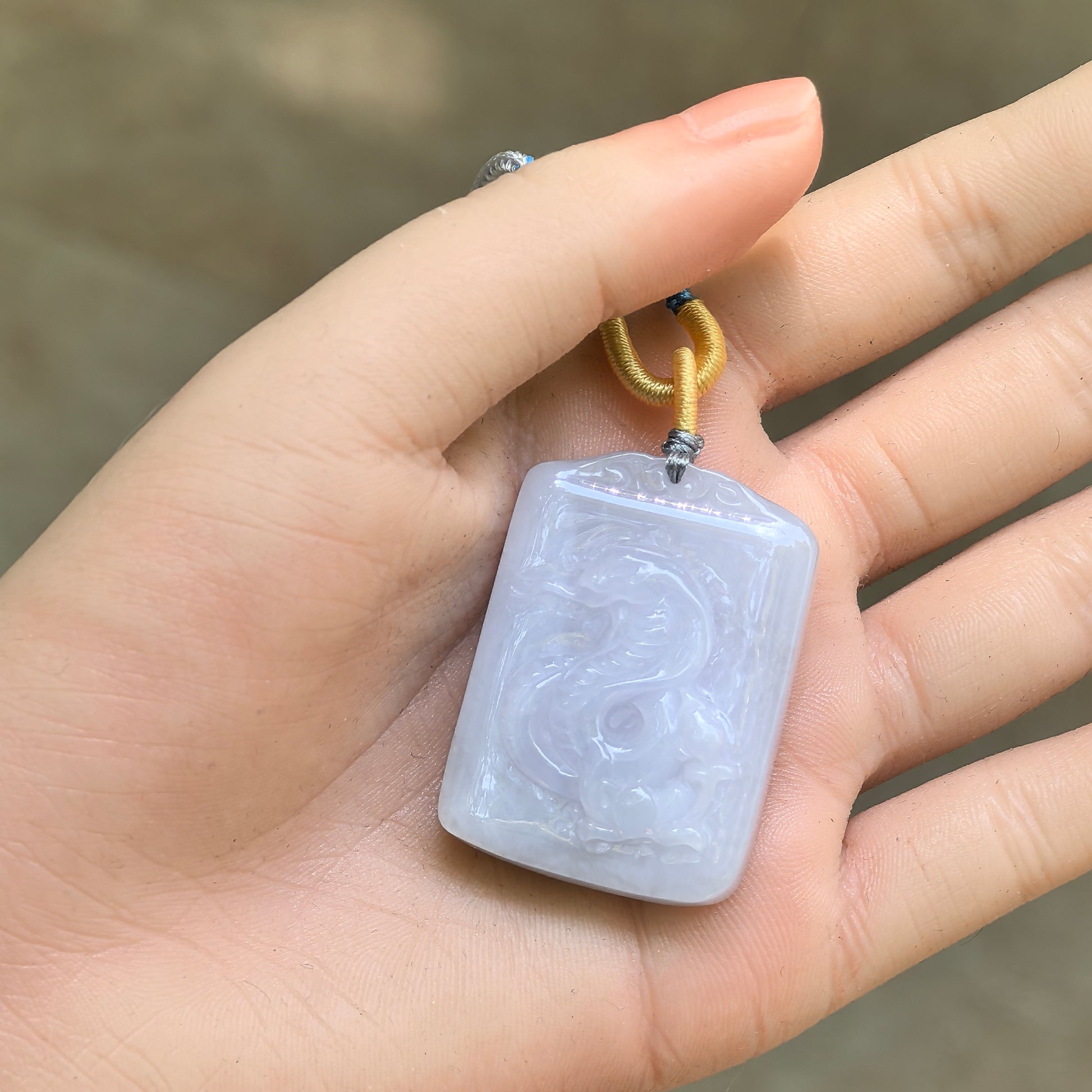 Natural Grade-A white jadeite snake pendant displayed in hand with attached cord.