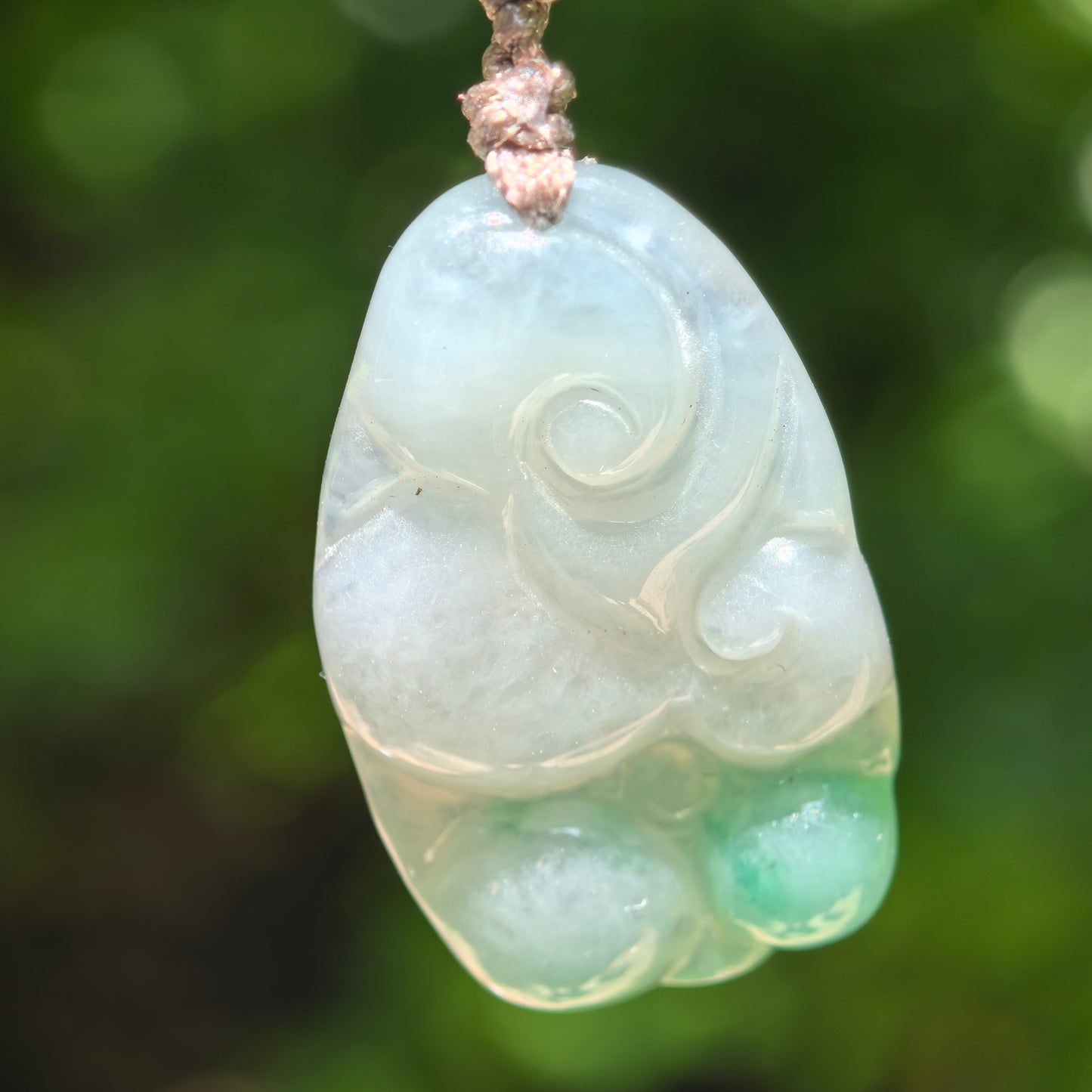 Natural Grade-A glutinous light green Ruyi jadeite pendant with vivid green accent hanging on cord.