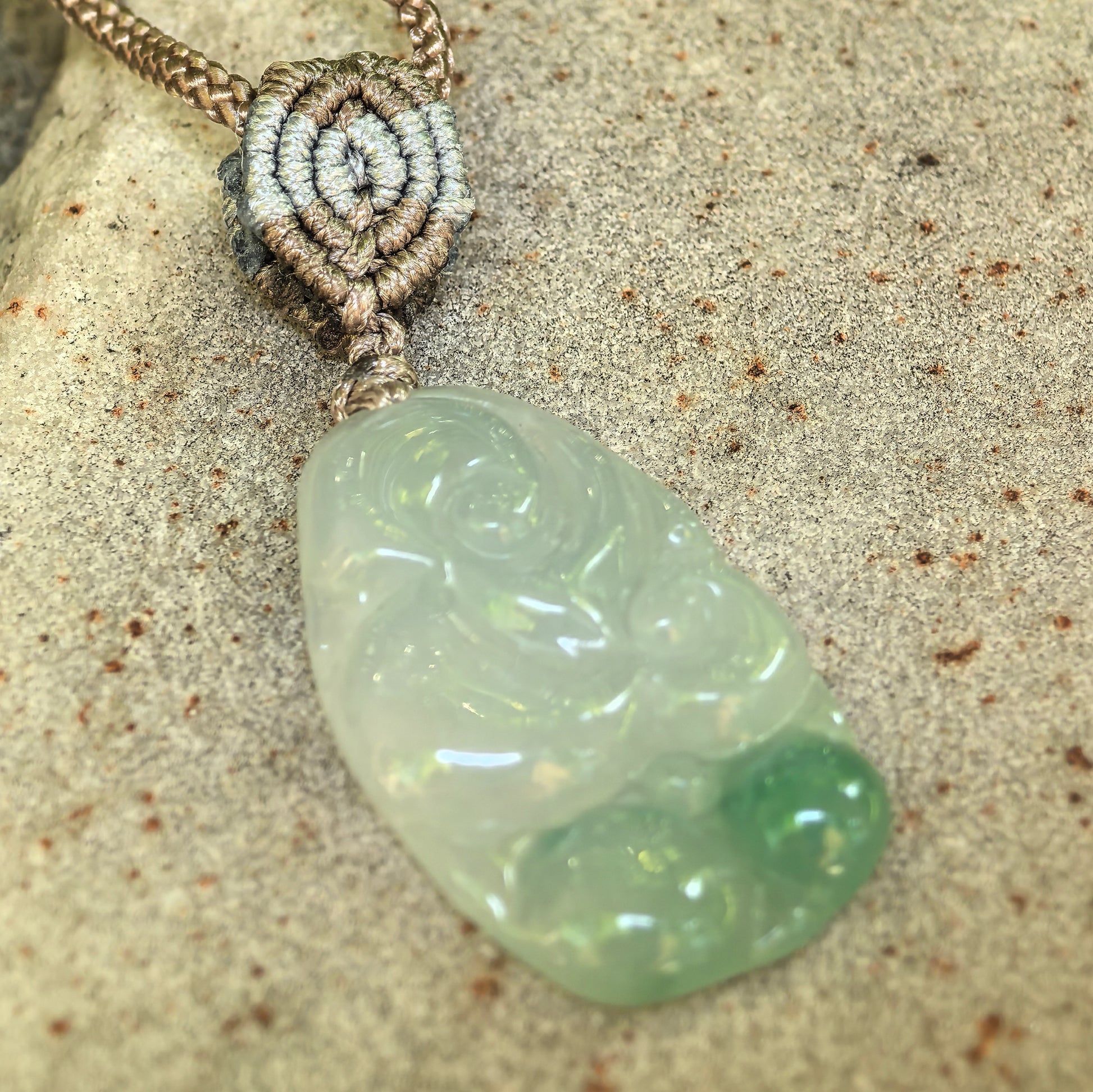 Close-up of light green Ruyi jadeite pendant showing smooth carving and icy-gel texture.