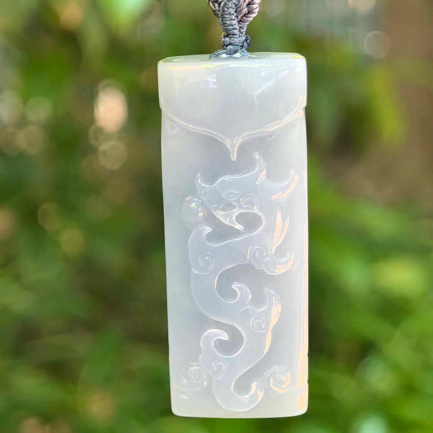 Close-up of carved dragon motif on blue-lavender Burmese jadeite pendant with antique-style details.