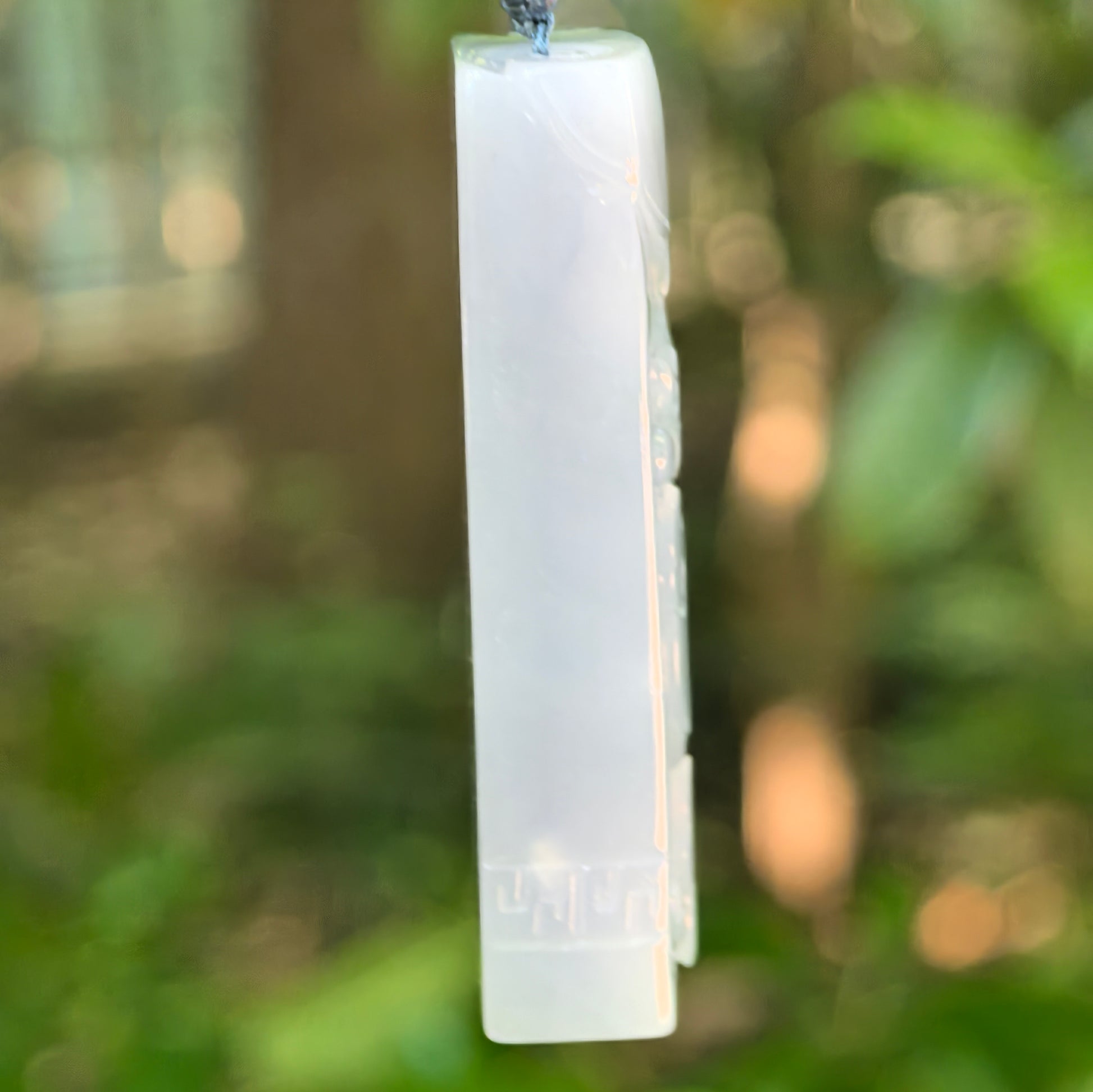 Side view of thick blue-lavender jadeite dragon pendant showing substantial depth and smooth polished edge.