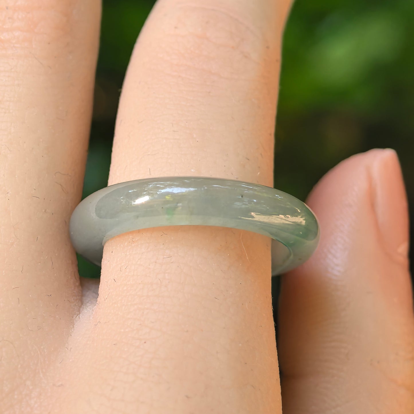 Light green jadeite ring band shown from different angles, highlighting its rounded profile and soft translucency.