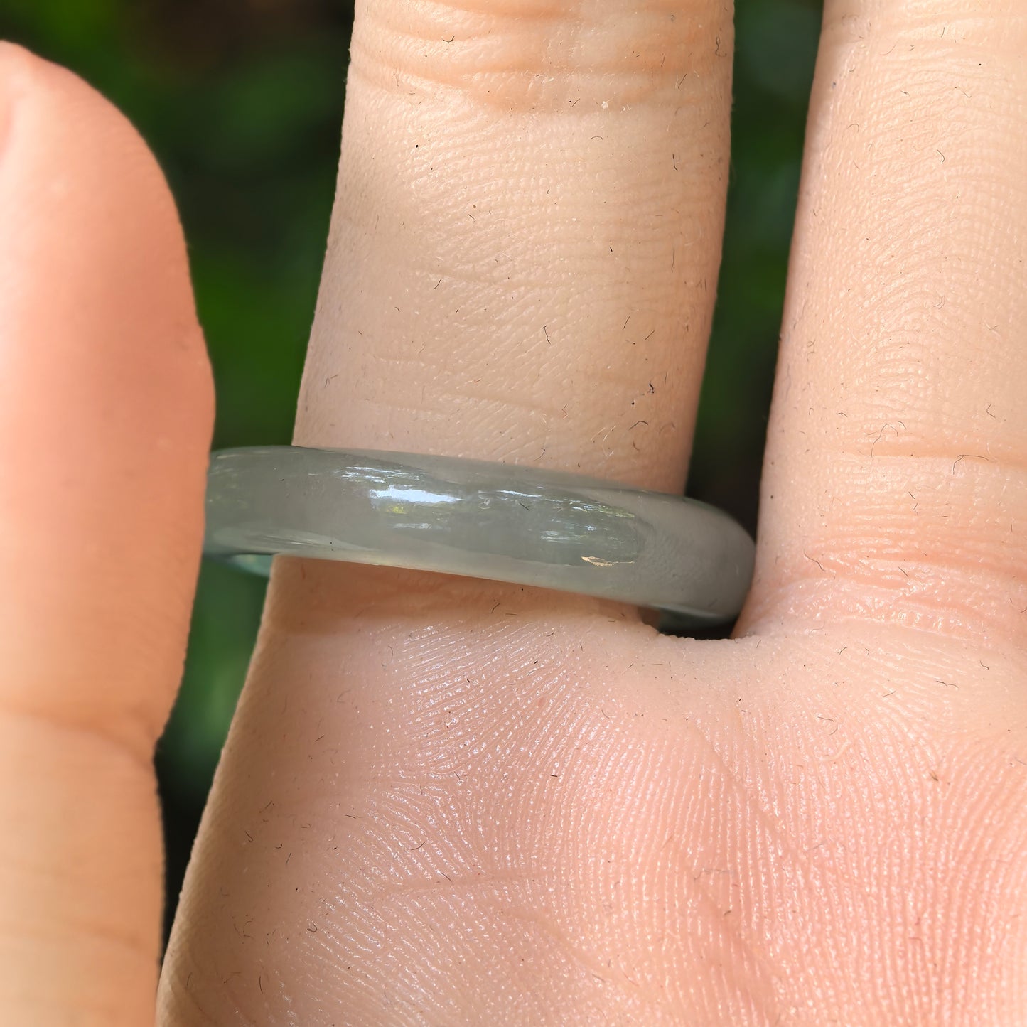 Light green jadeite ring band shown from different angles, highlighting its rounded profile and soft translucency.