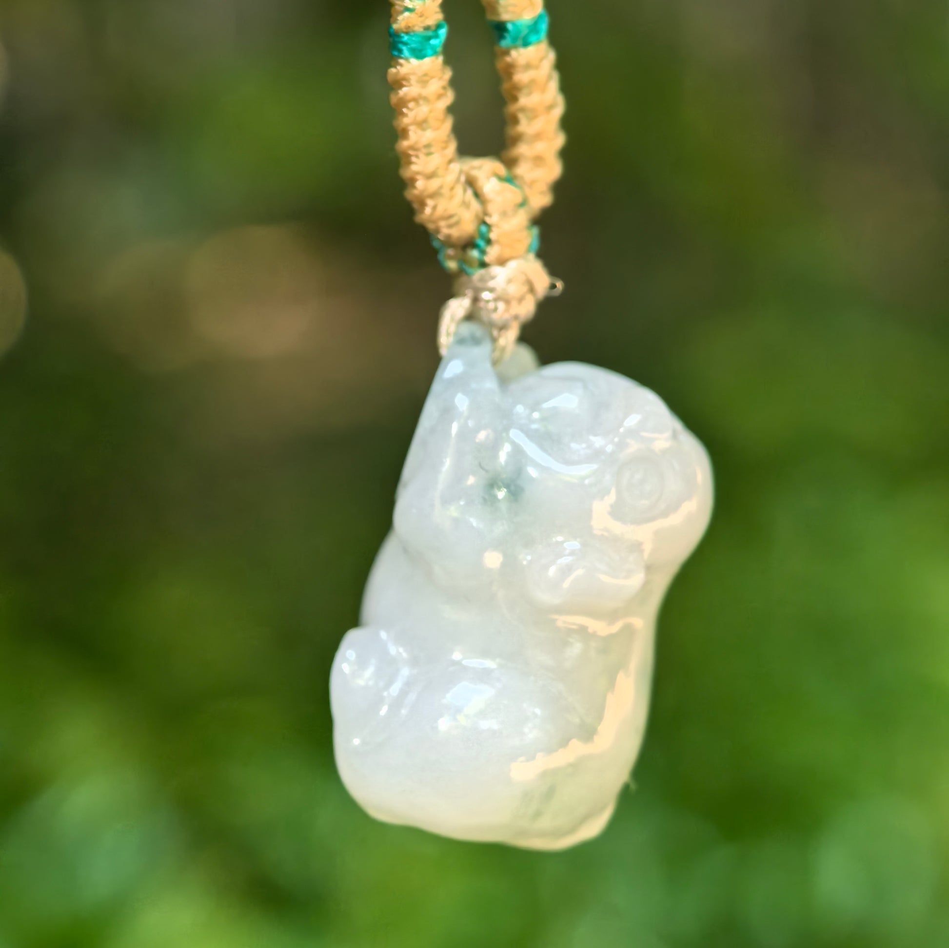 Side view of the small pig jadeite pendant showing its compact thickness and polished surface.