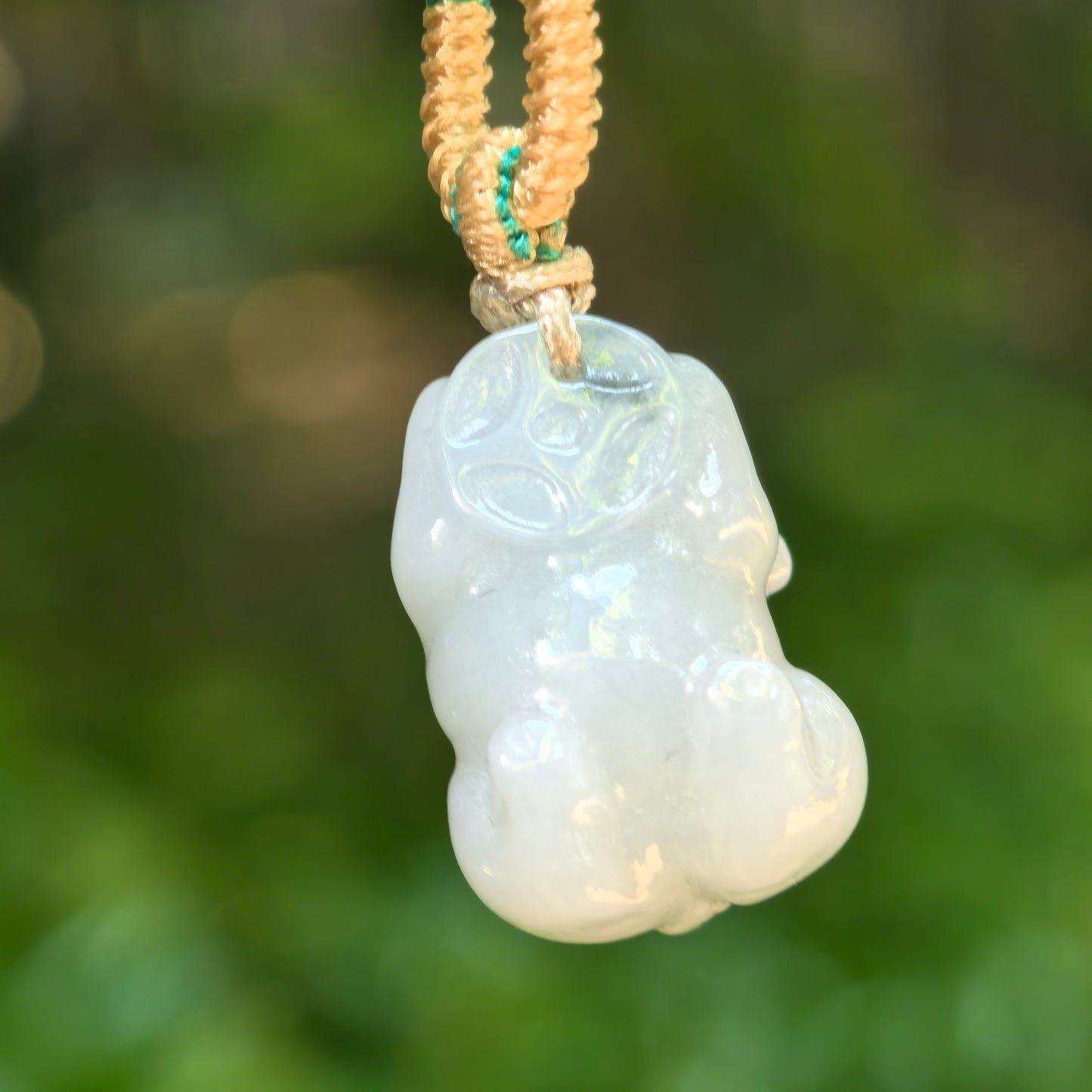 Back view of the natural jadeite pig pendant with a smooth rounded form and subtle translucency.
