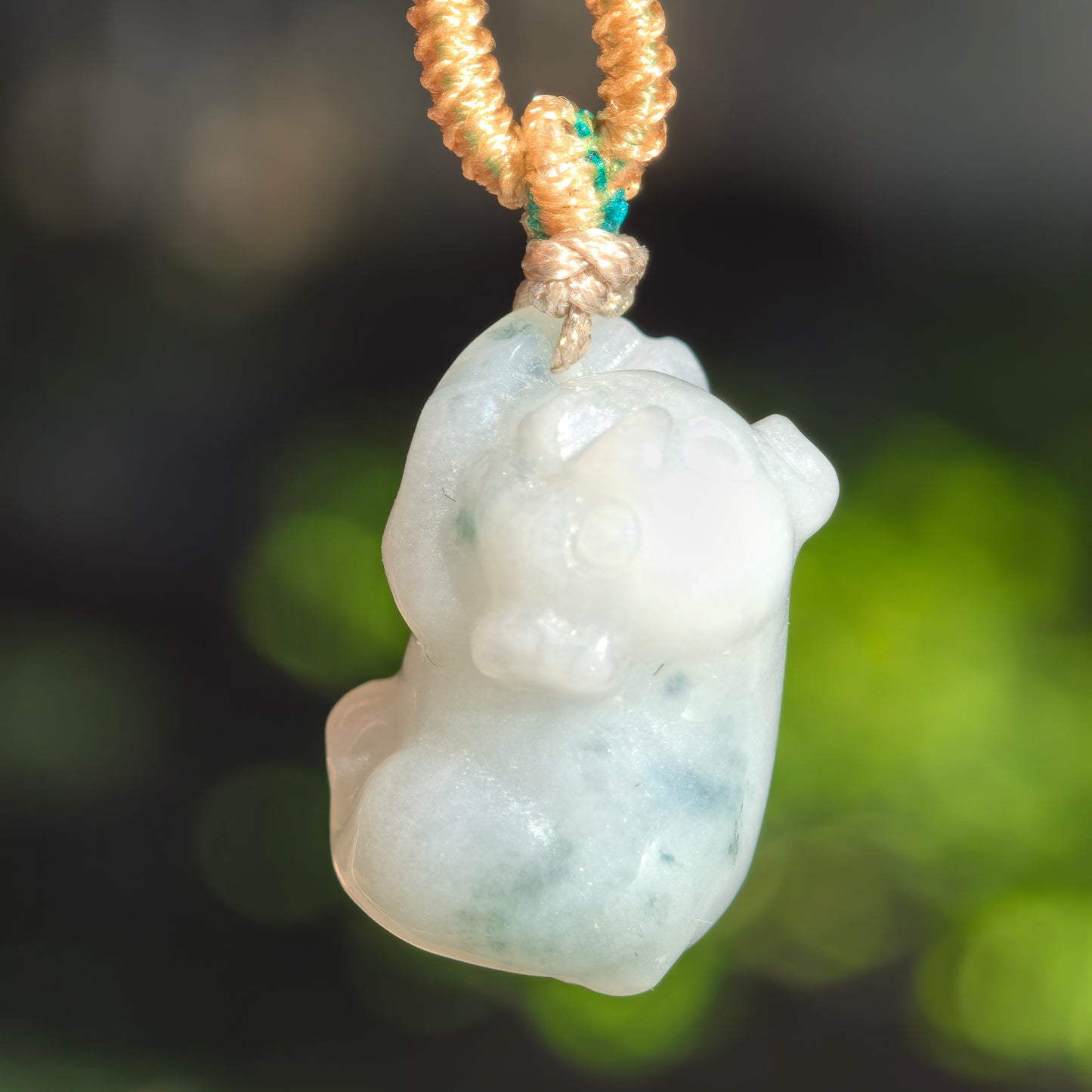 Front angled view of the pig jadeite pendant showing its expressive face and natural green mottling.