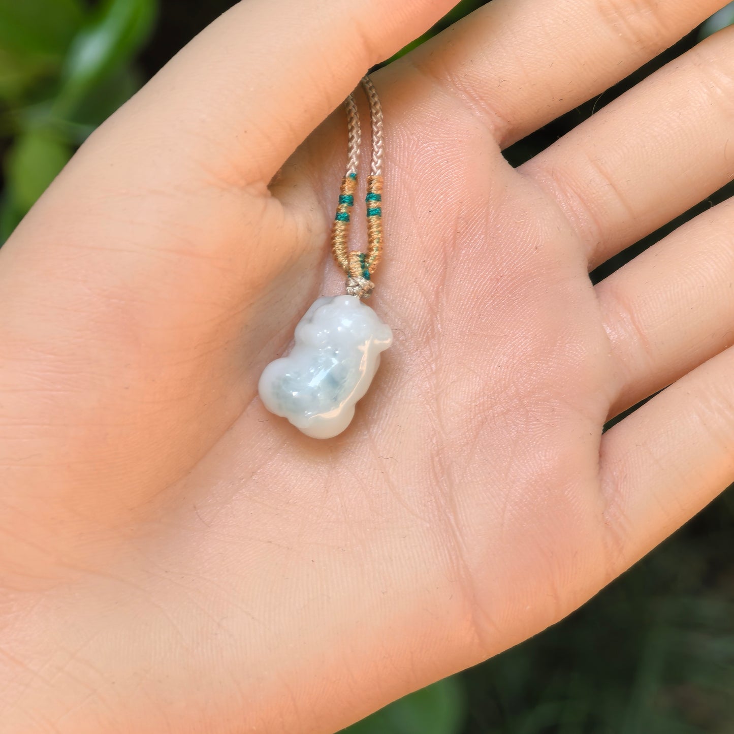 Small three-dimensional pig jadeite pendant shown in hand for size reference.