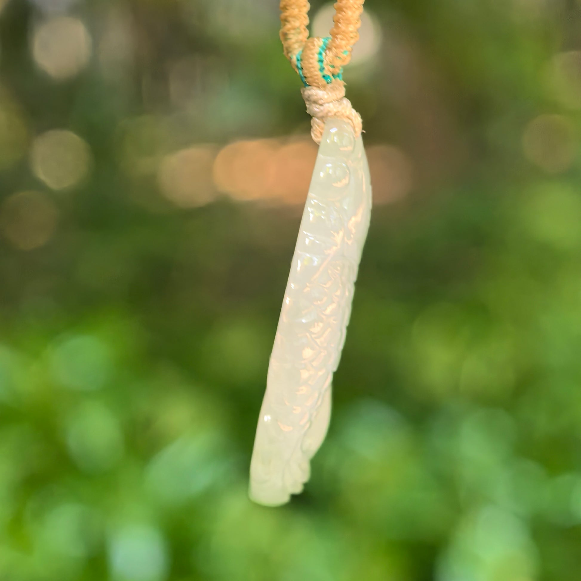 Side view of pale green fish jadeite pendant showing slim profile
