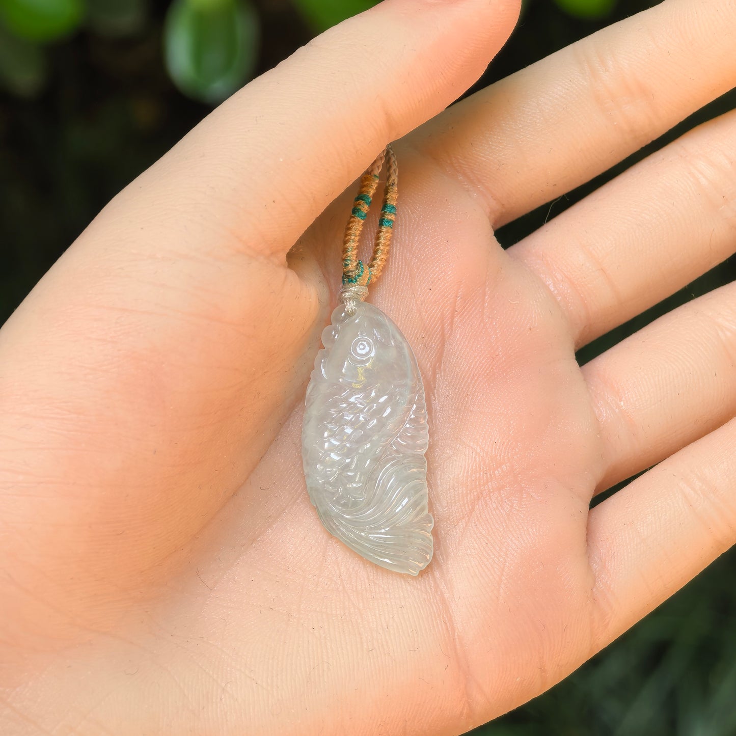 Natural Burmese jade fish pendant shown in hand for size reference

