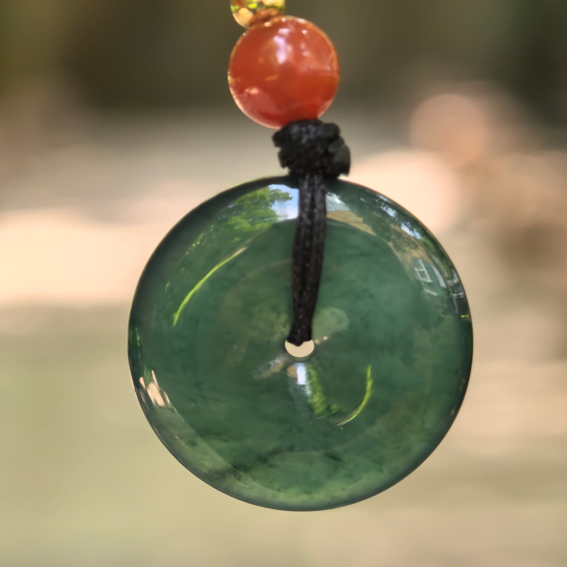Natural Grade-A icy glutinous teal blue Guatemalan jadeite Peace Pendant hanging with black cord and red bead.

