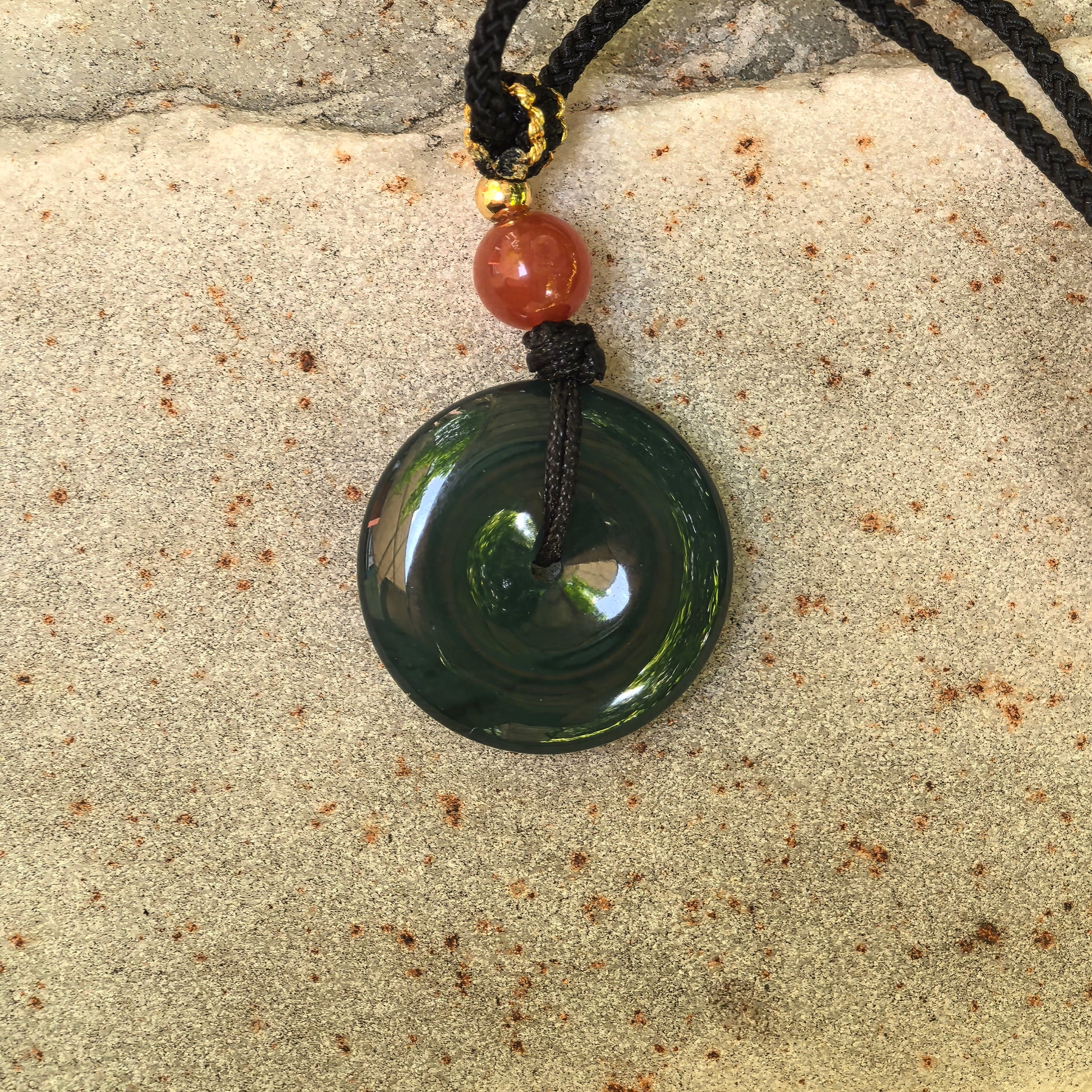Close-up of icy glutinous teal blue Peace Pendant on stone background with glossy polished surface.
