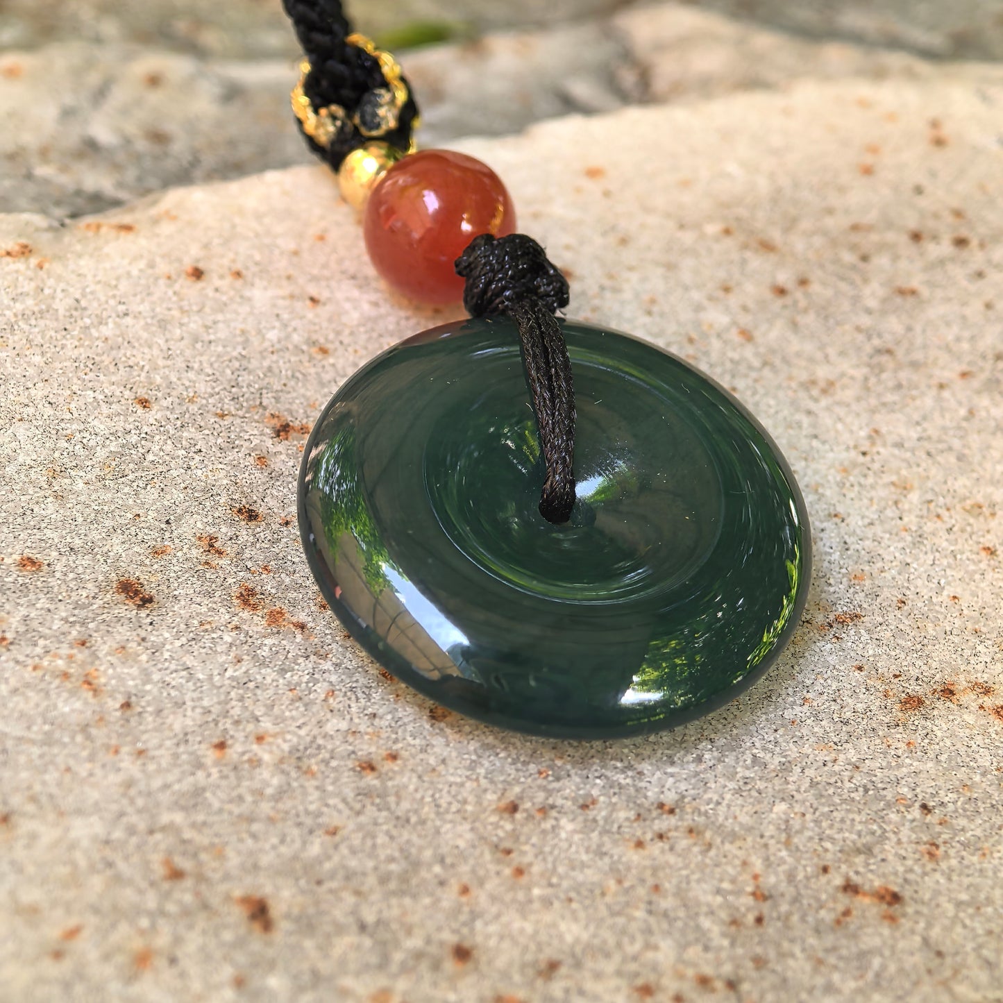 Backlit teal blue Guatemalan jadeite Peace Pendant showing good translucency and smooth round shape.
