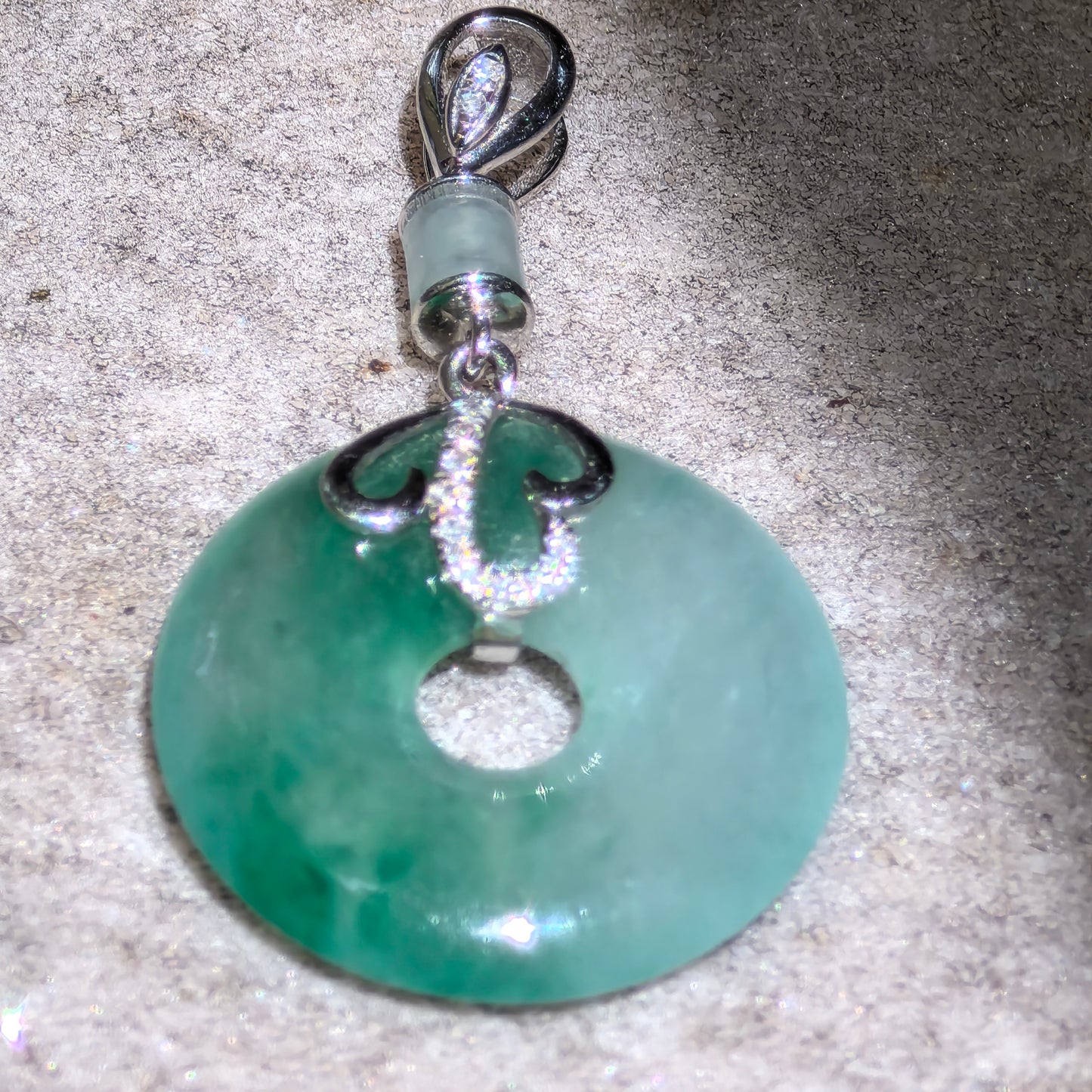 Natural Grade-A green donut jadeite pendant showing icy translucency and diamond-accented 18K gold detail.
