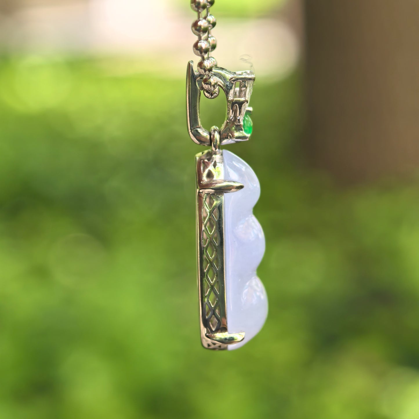 Side view of petite violet bean jadeite pendant showing 18K gold setting and raised jadeite carving.
