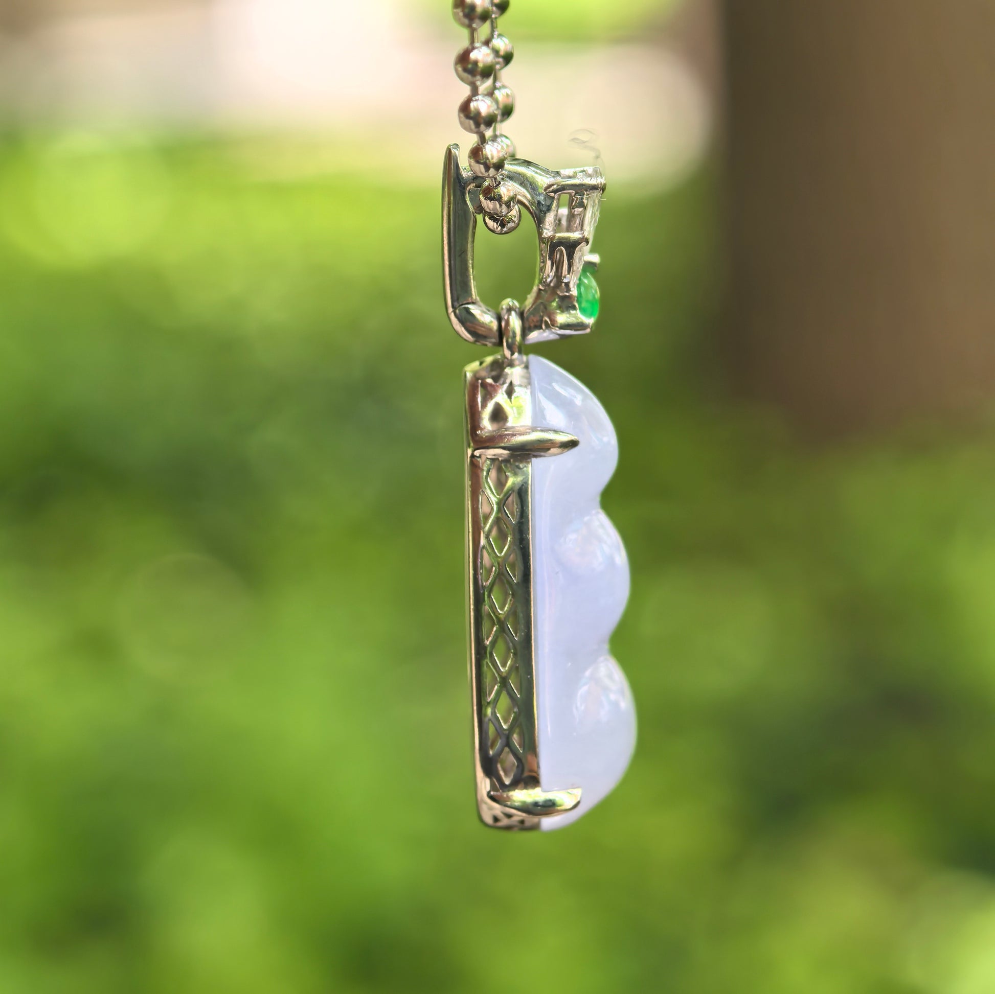 Side view of petite violet bean jadeite pendant showing 18K gold setting and raised jadeite carving.
